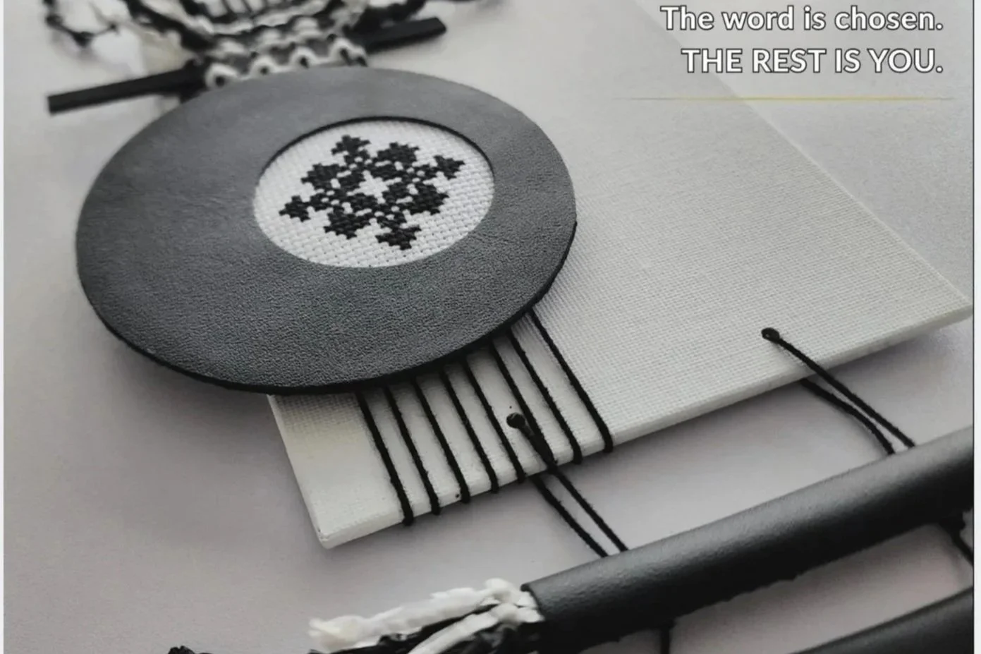 Black and white Encoded Intention embroidered word ornament incorporated into a handmade textile object