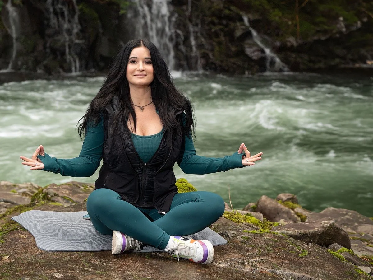 Annette meditating beside a waterfall
