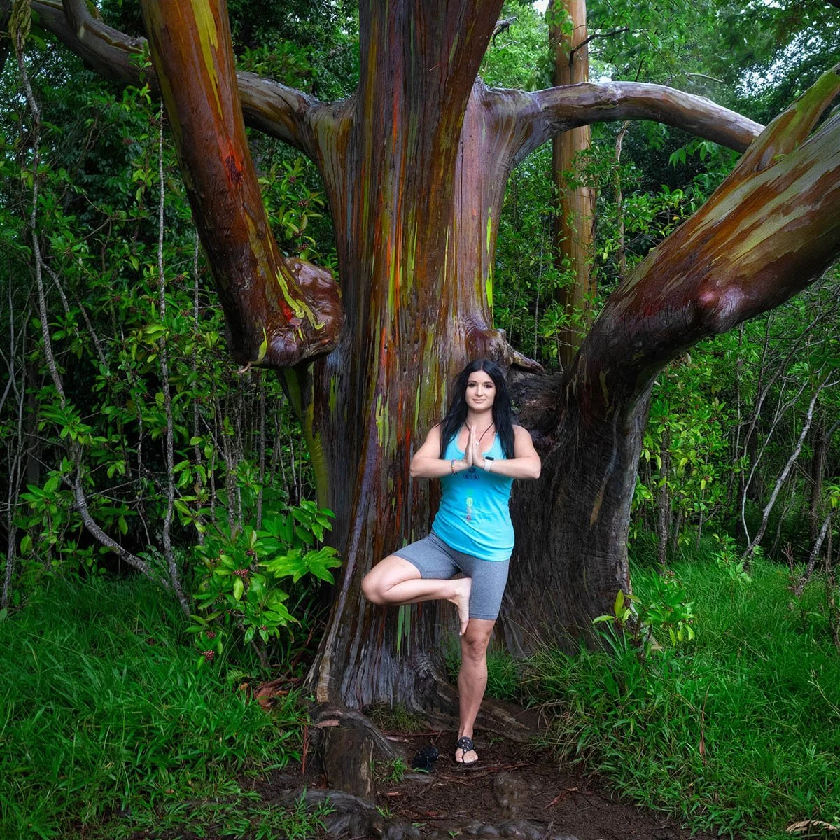 Annette practicing beside a colorful tree in lush tropical greenery