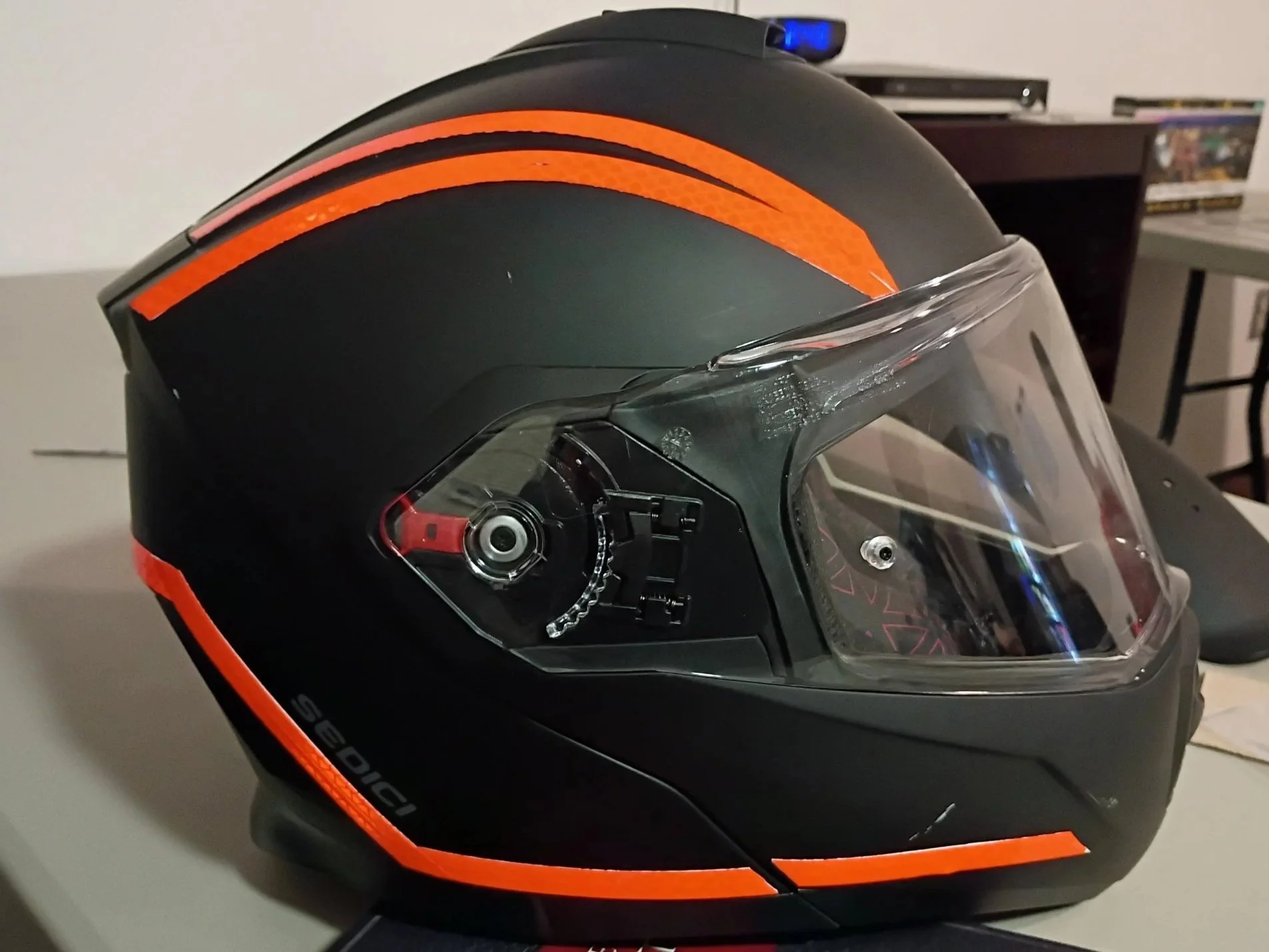 Close-up of a motorcycle helmet with black and orange design and a transparent visor.