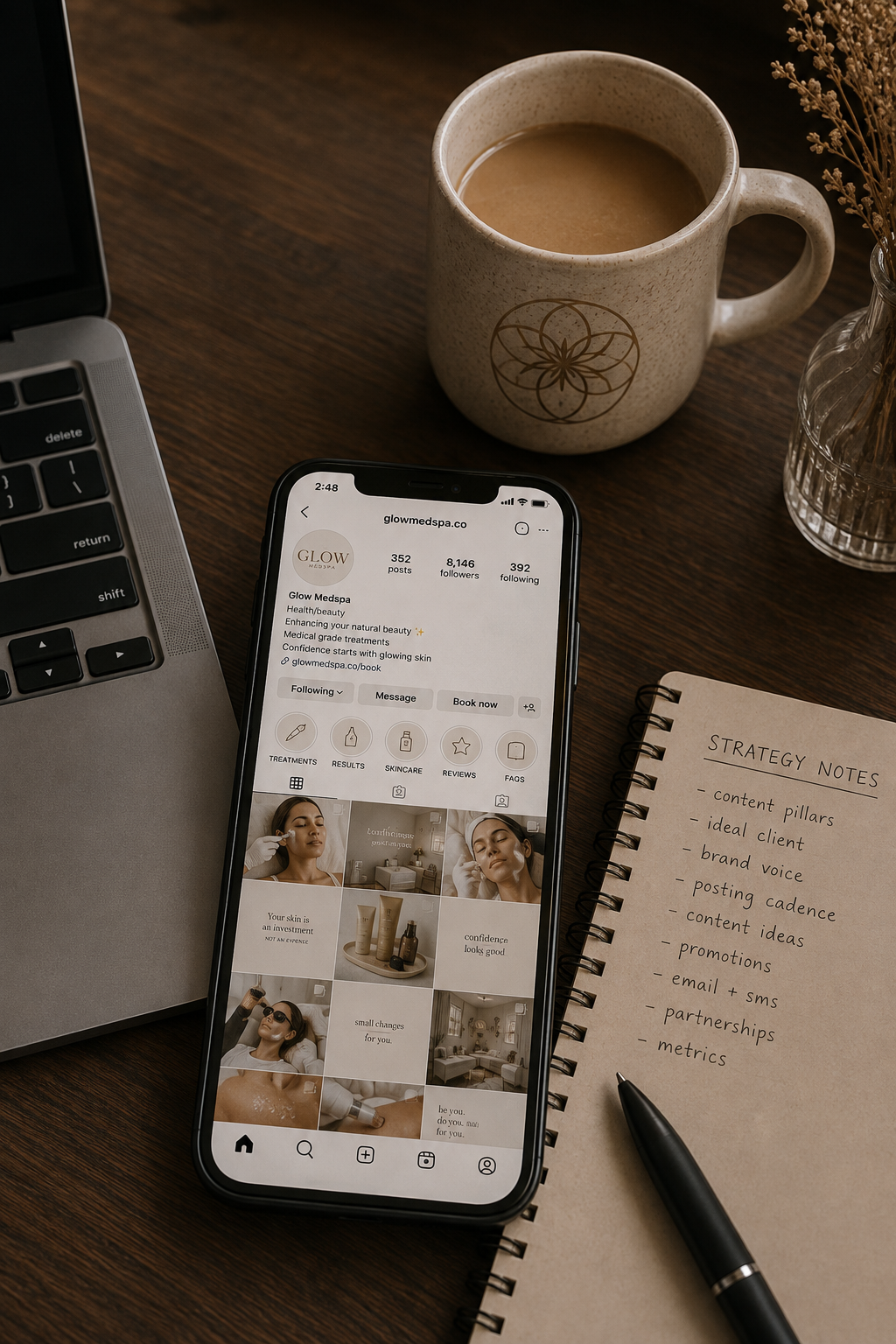 A workspace with a laptop, a coffee mug, a smartphone displaying an Instagram profile for Glow Medspa, a notebook with strategy notes, and a black pen.