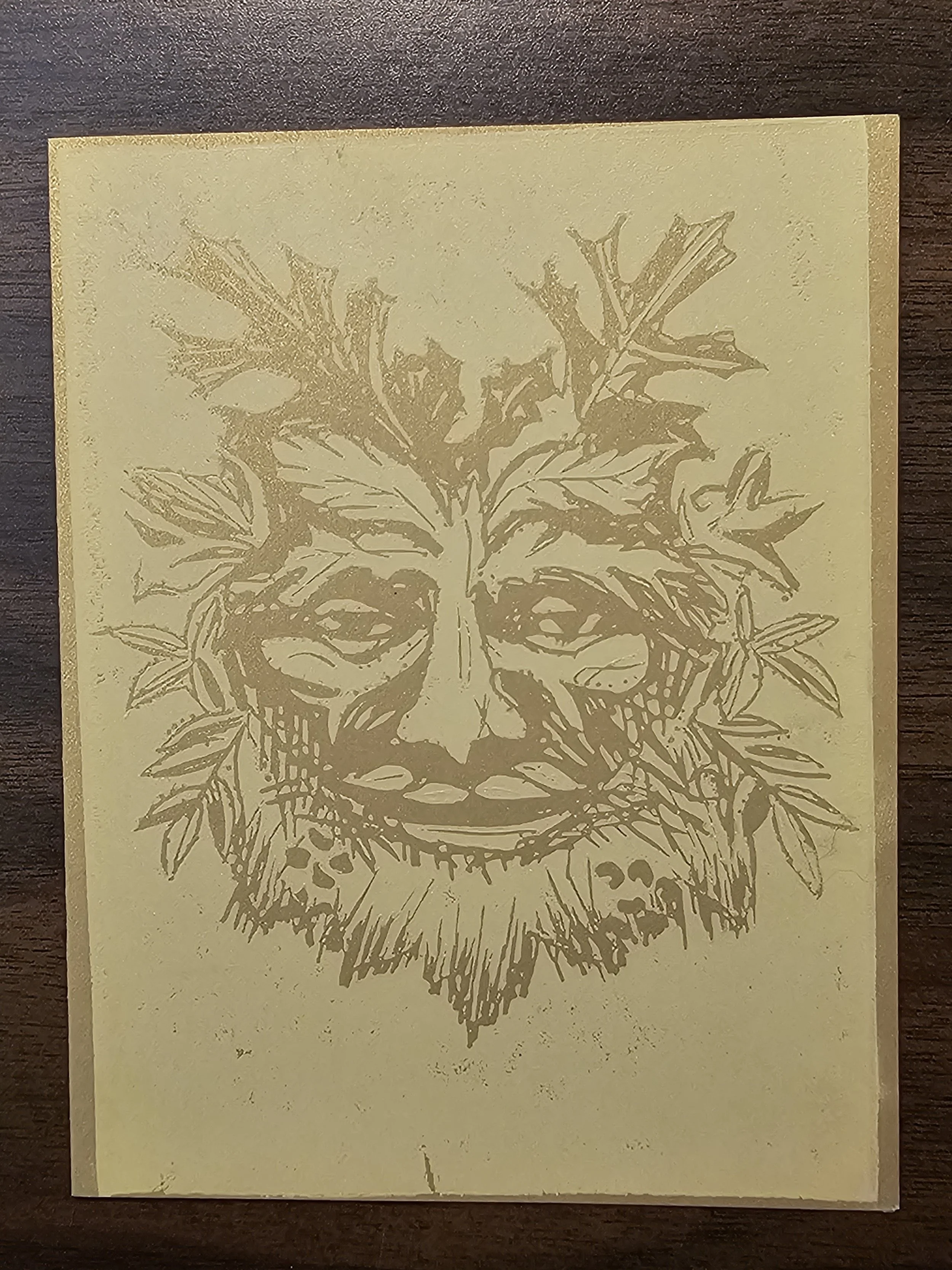 A detailed illustration of a potted plant, possibly a holly or similar with spiky leaves, printed in gold on beige paper.