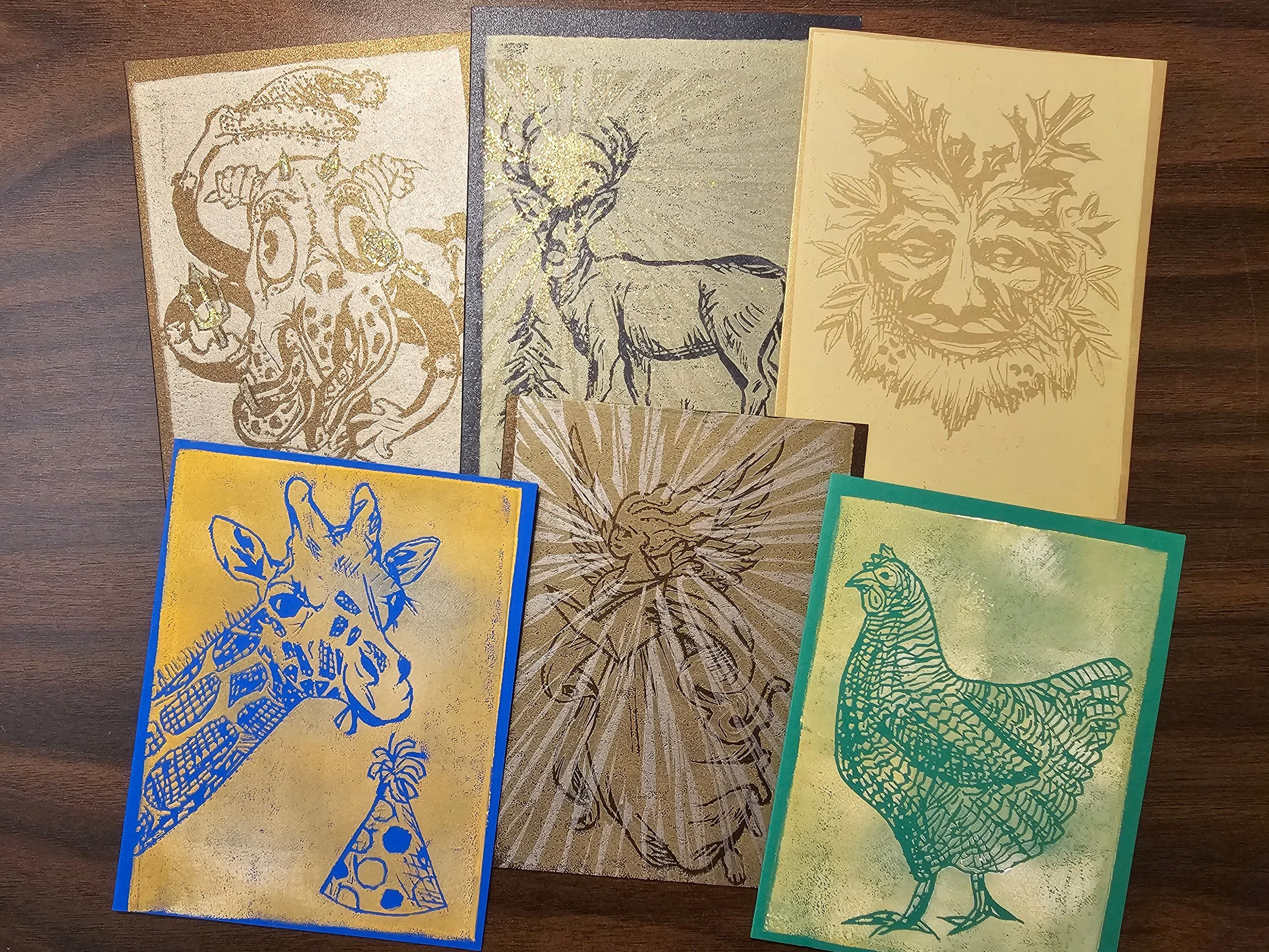 A collection of metallic gold, silver, and colored cards with intricate designs of a lion, a deer, a fox, and a snake, placed on a wooden surface.