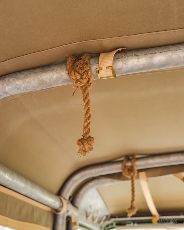 A brown rope tied to a bag strap hanging from a metal bar in a gym or fitness studio.