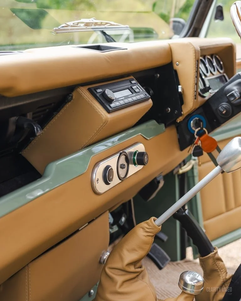 Close-up of a vintage car dashboard with tan upholstery, a radio, and steering column.