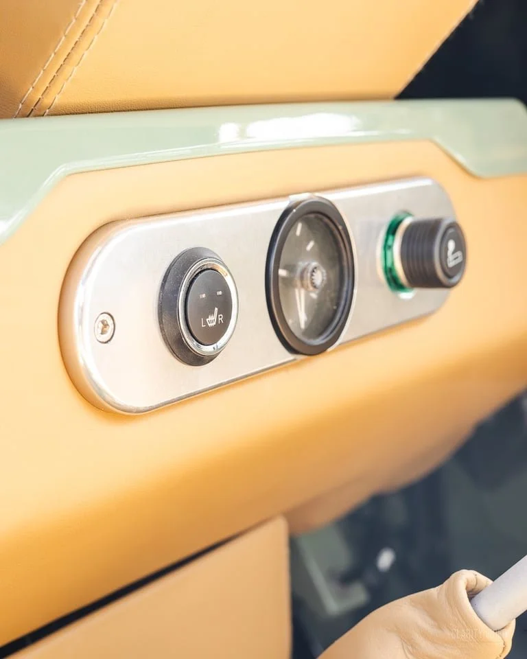 Car seatback with controls for seat heating and a clock, with leather upholstery.
