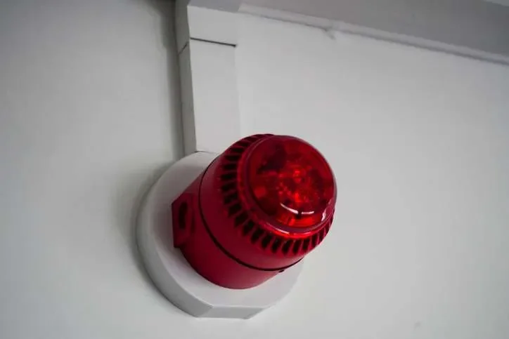 Red fire alarm mounted on a white ceiling