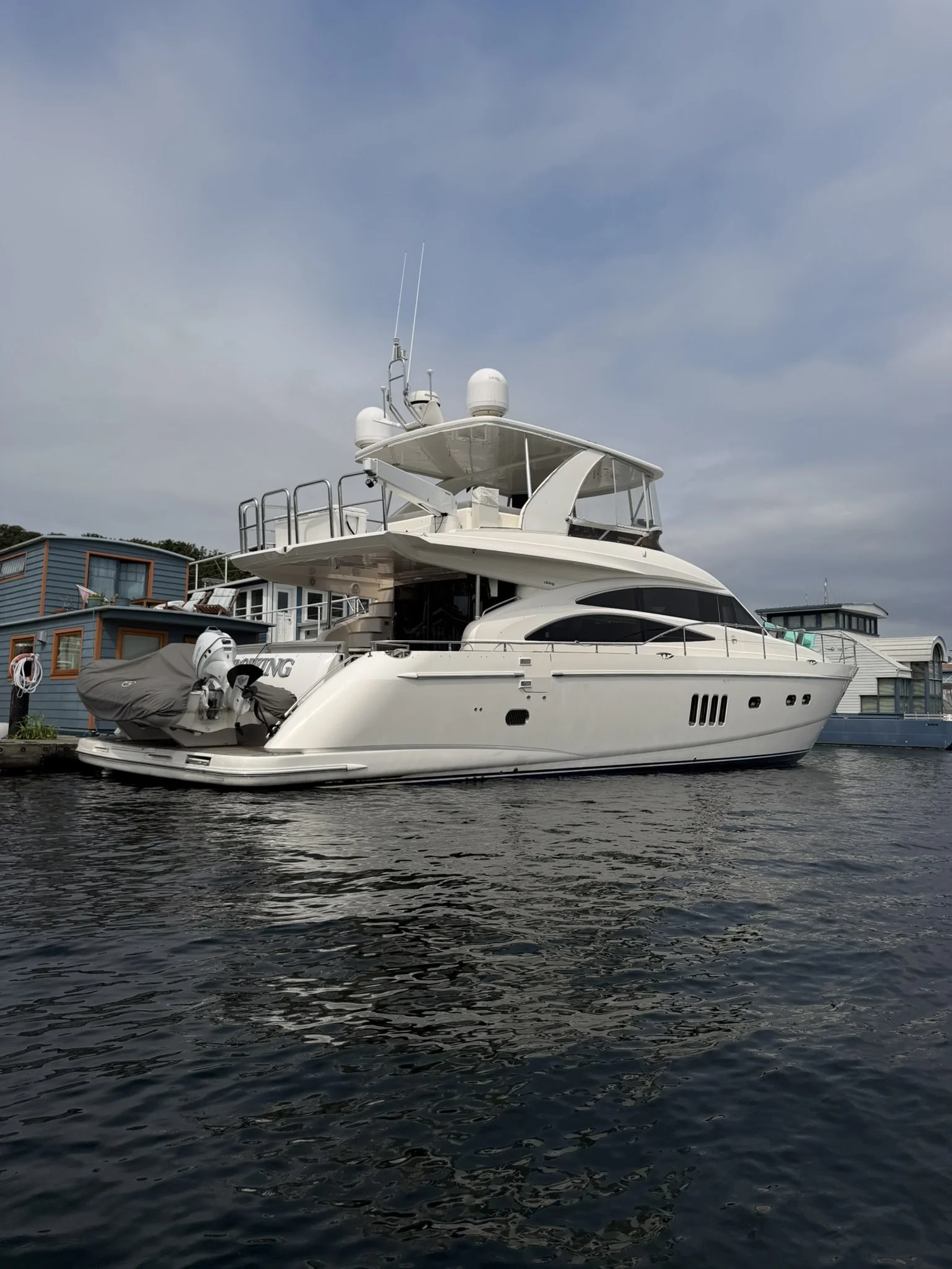 A white motor yacht cruising on the ocean with a city skyline in the background.