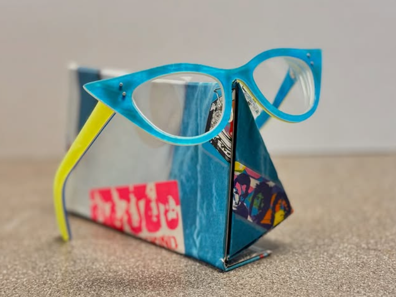 Colorful paper craft shaped like a house with a pair of blue sunglasses on top.