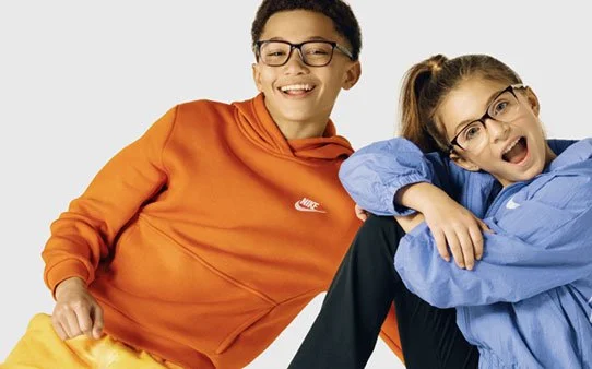 Two kids, a boy and a girl, smiling and playing together against a white background.