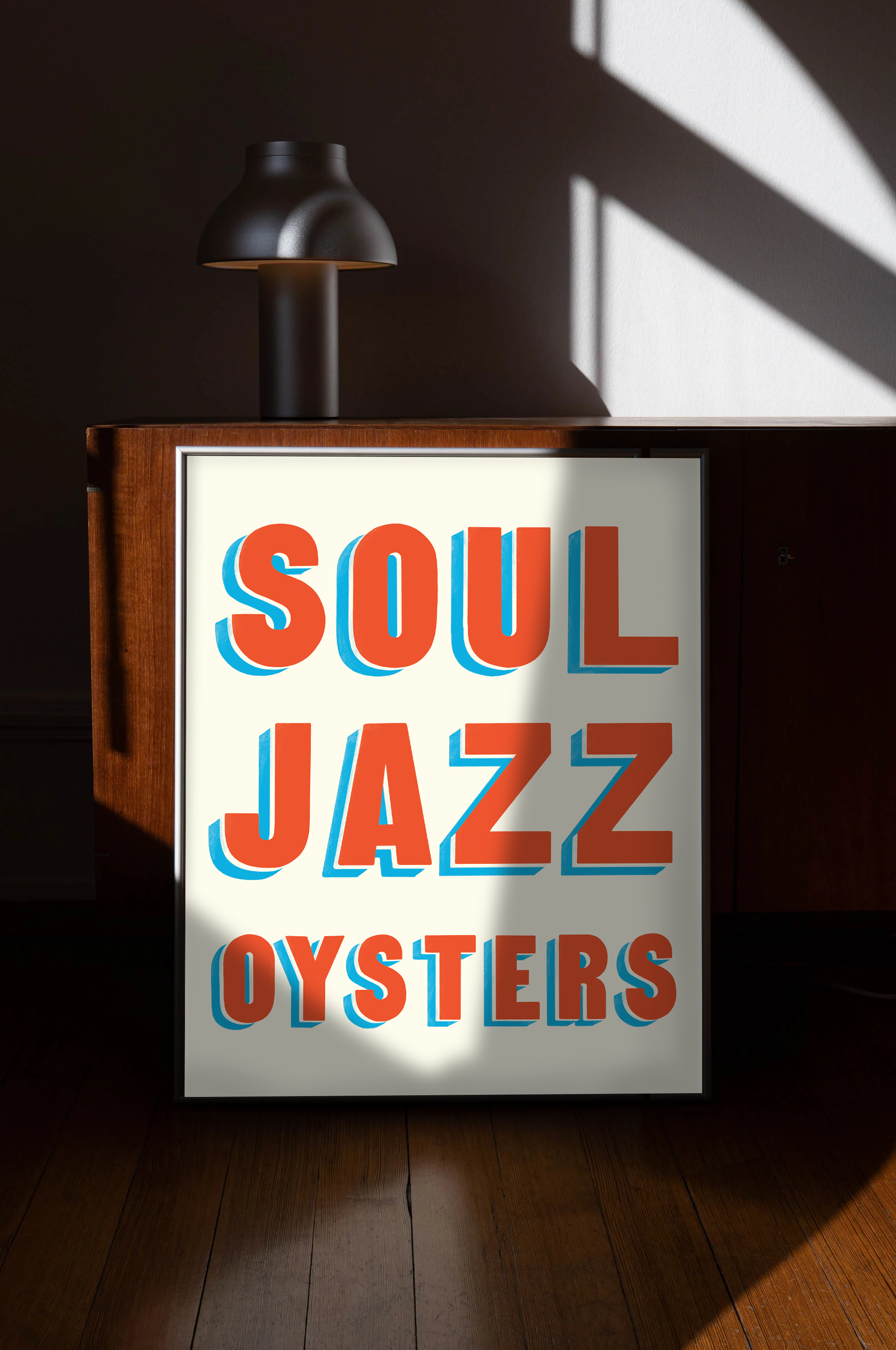 Brightly lit sign with the words "SOUL JAZZ OYSTERS" in orange and blue lettering, standing on a wooden floor, with a black lamp on top casting a shadow on the wall.