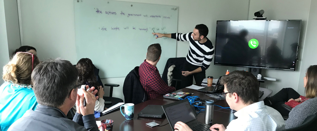 David pointing to a whiteboard with information about plain language and content design best practices