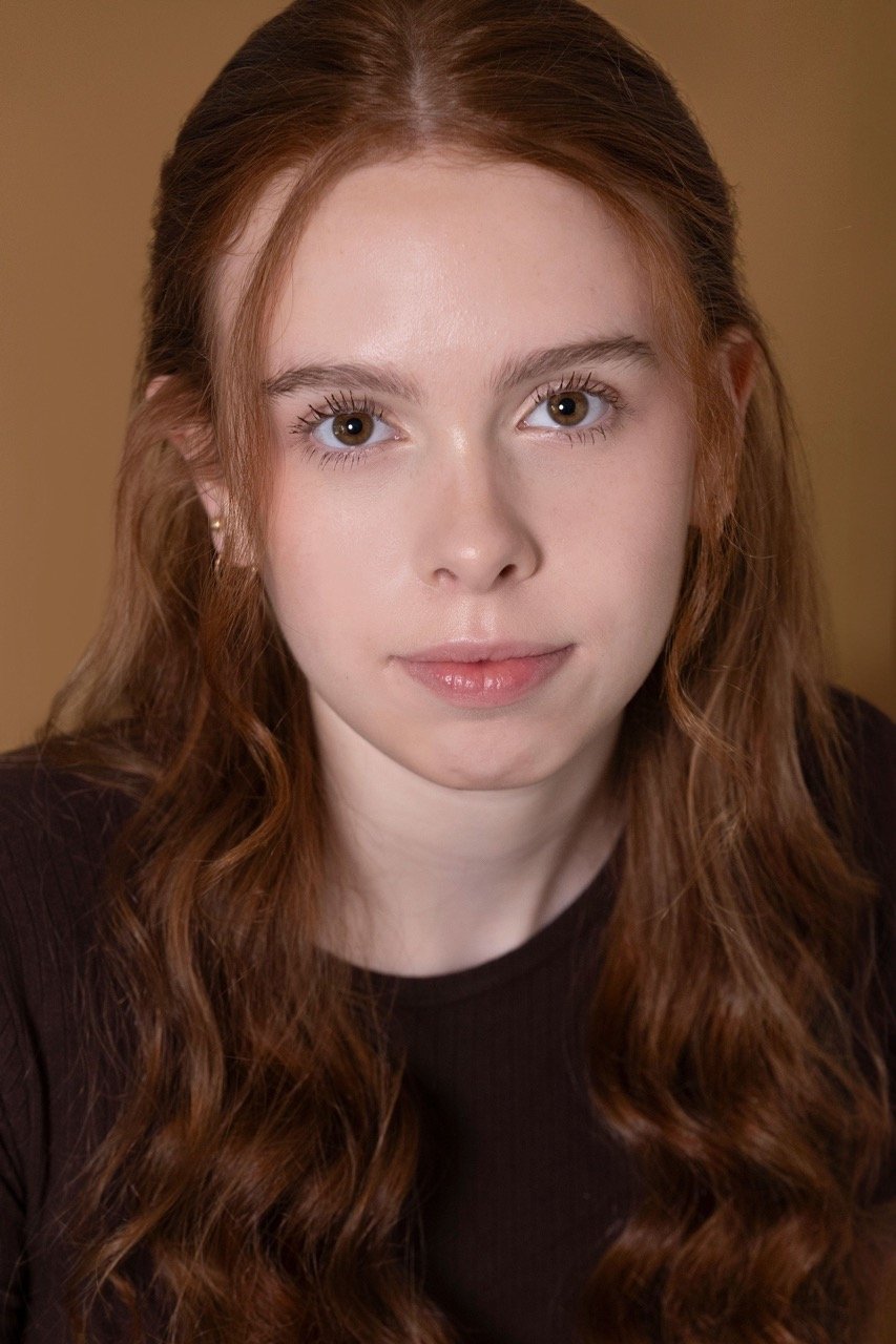 Kassia with her hair half up, looking serious