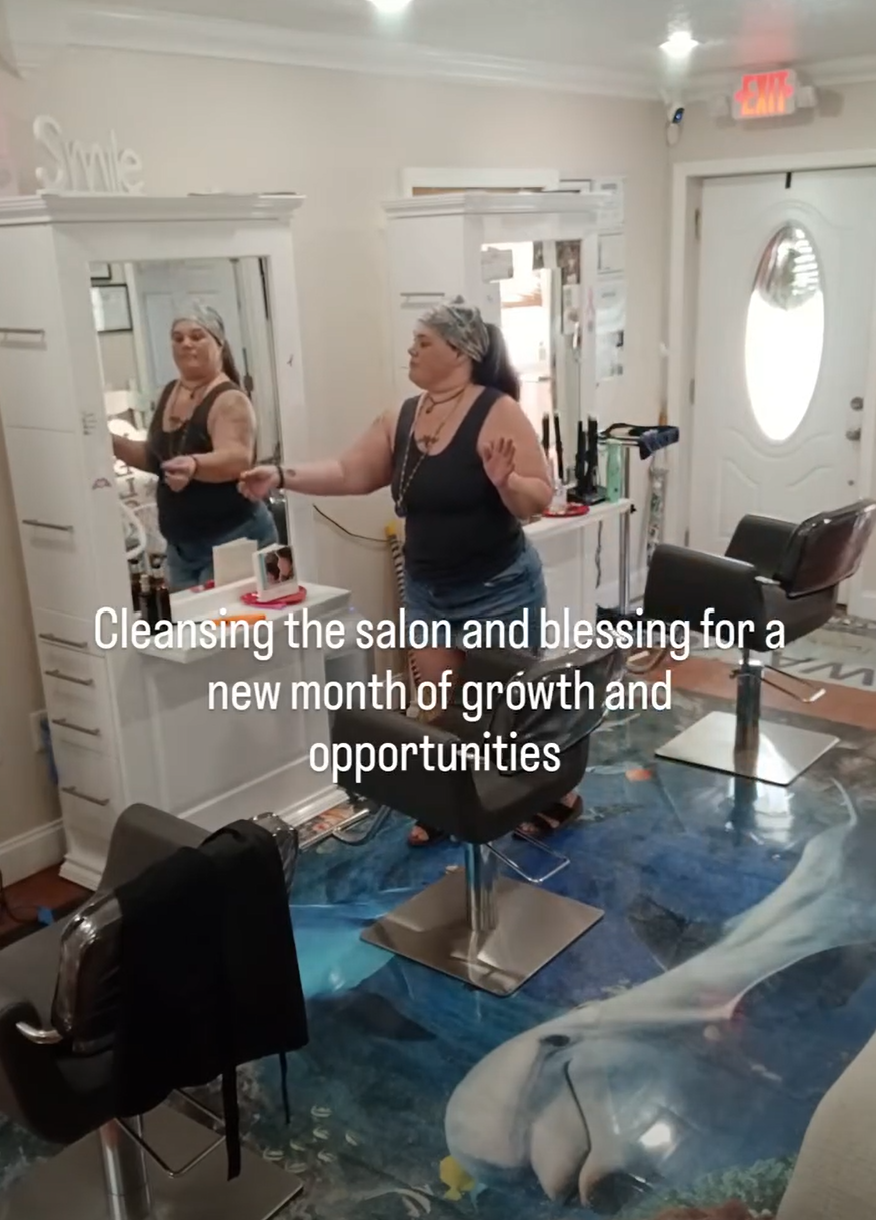 Two women with hair covers in a salon, practicing cleansing and blessing for new growth and opportunities, with salon chairs and mirrors visible.