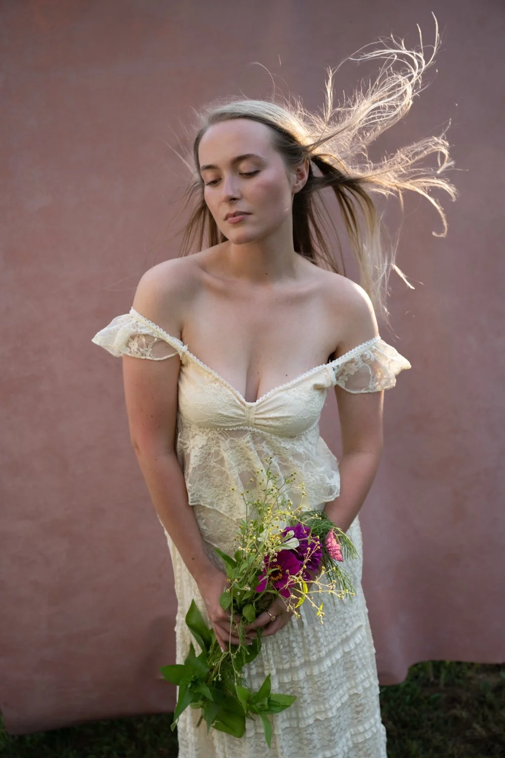 Portrait of a woman in an ivory lace dress against a hand-painted rose photography backdrop.