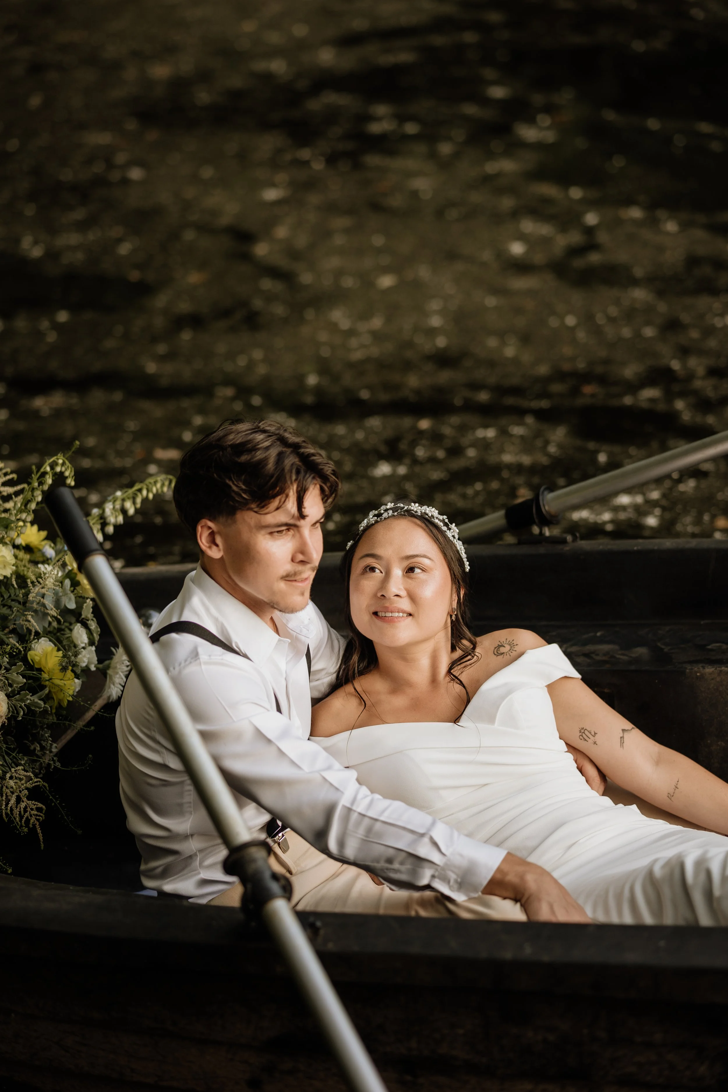 Un couple assis dans une barque sur l'eau, lors d'une séance photo de mariage, entouré de fleurs avec Maquillage de soirée sophistiqué pour un événement