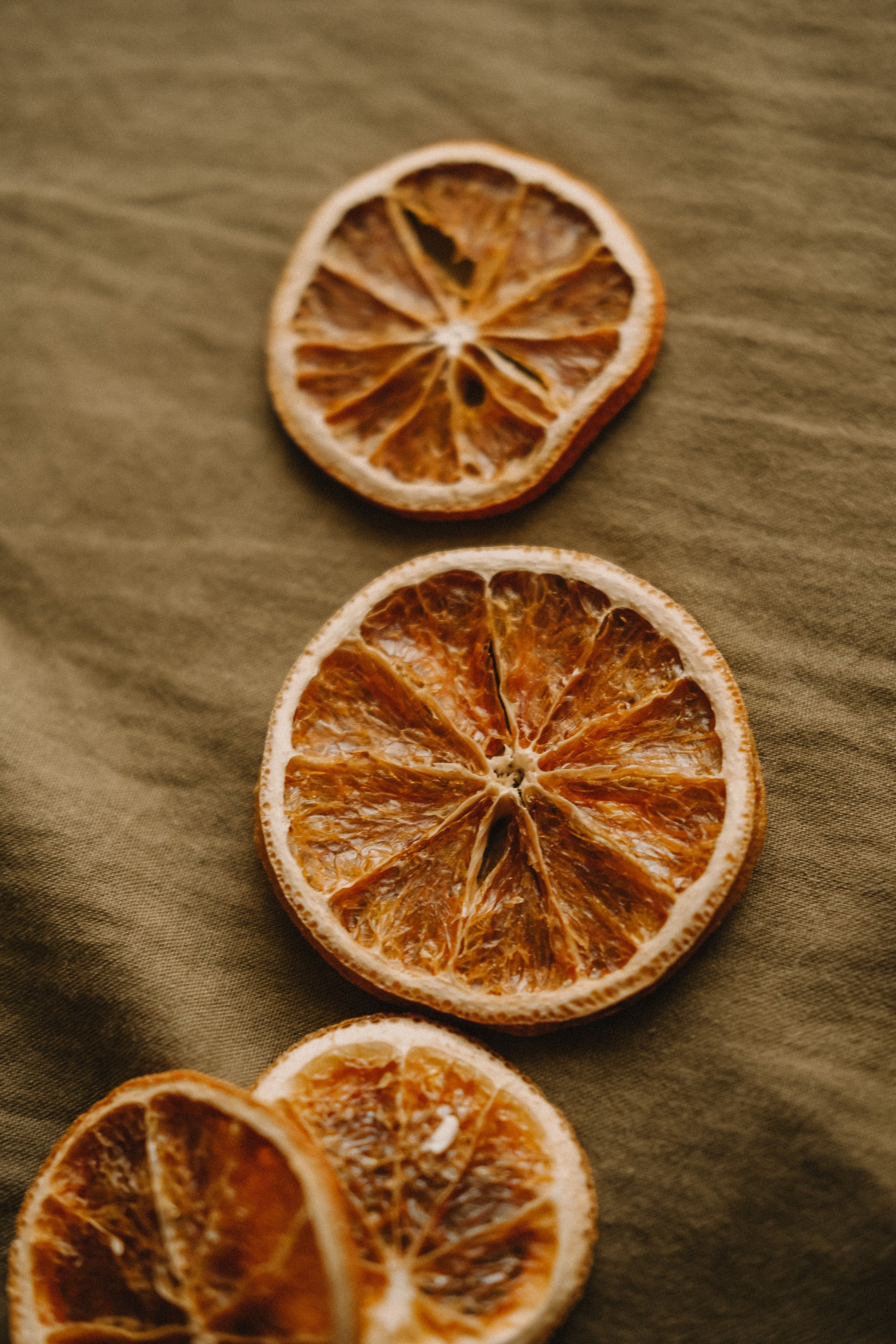 Close-up of dried orange slices on a textured green surface.