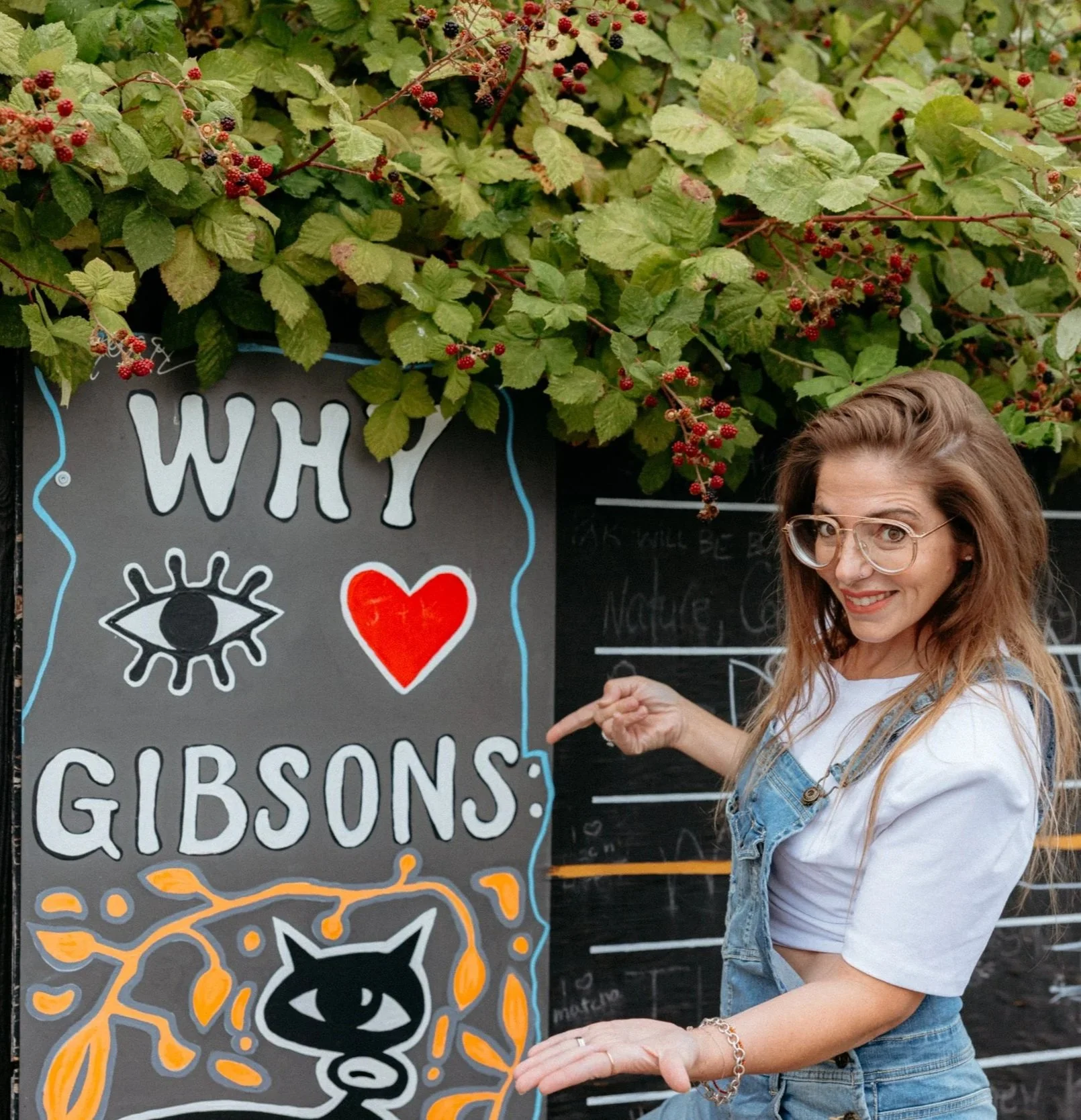Sara smiles and points to the I Love Gibsons Artwork