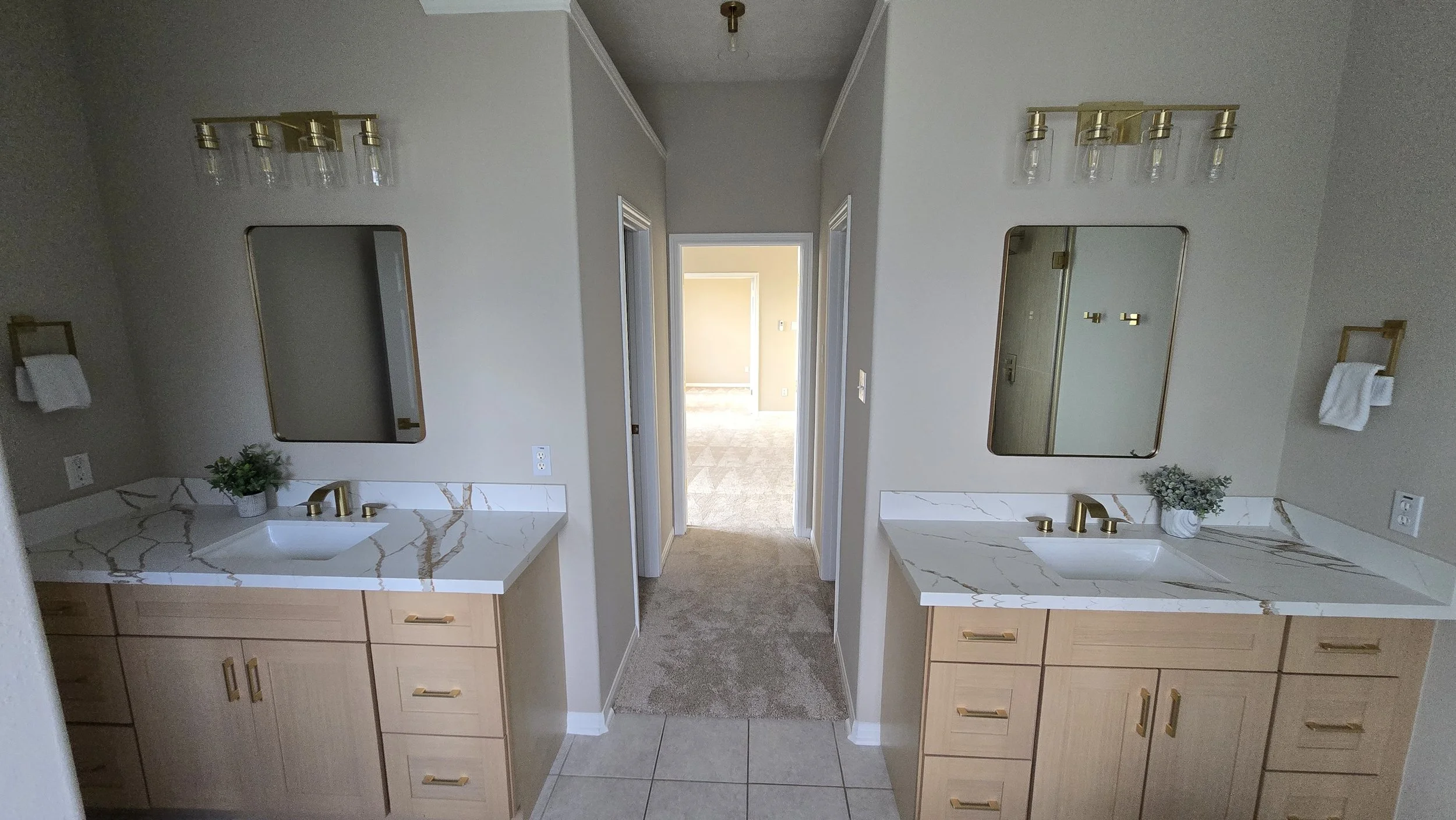 TurnKey Roofing & Restoration — A newly renovated / remodeled bathroom with double vanities featuring marble countertops and wooden cabinets, two mirrors, and a glass shower enclosure with brass hardware. Houston, Texas