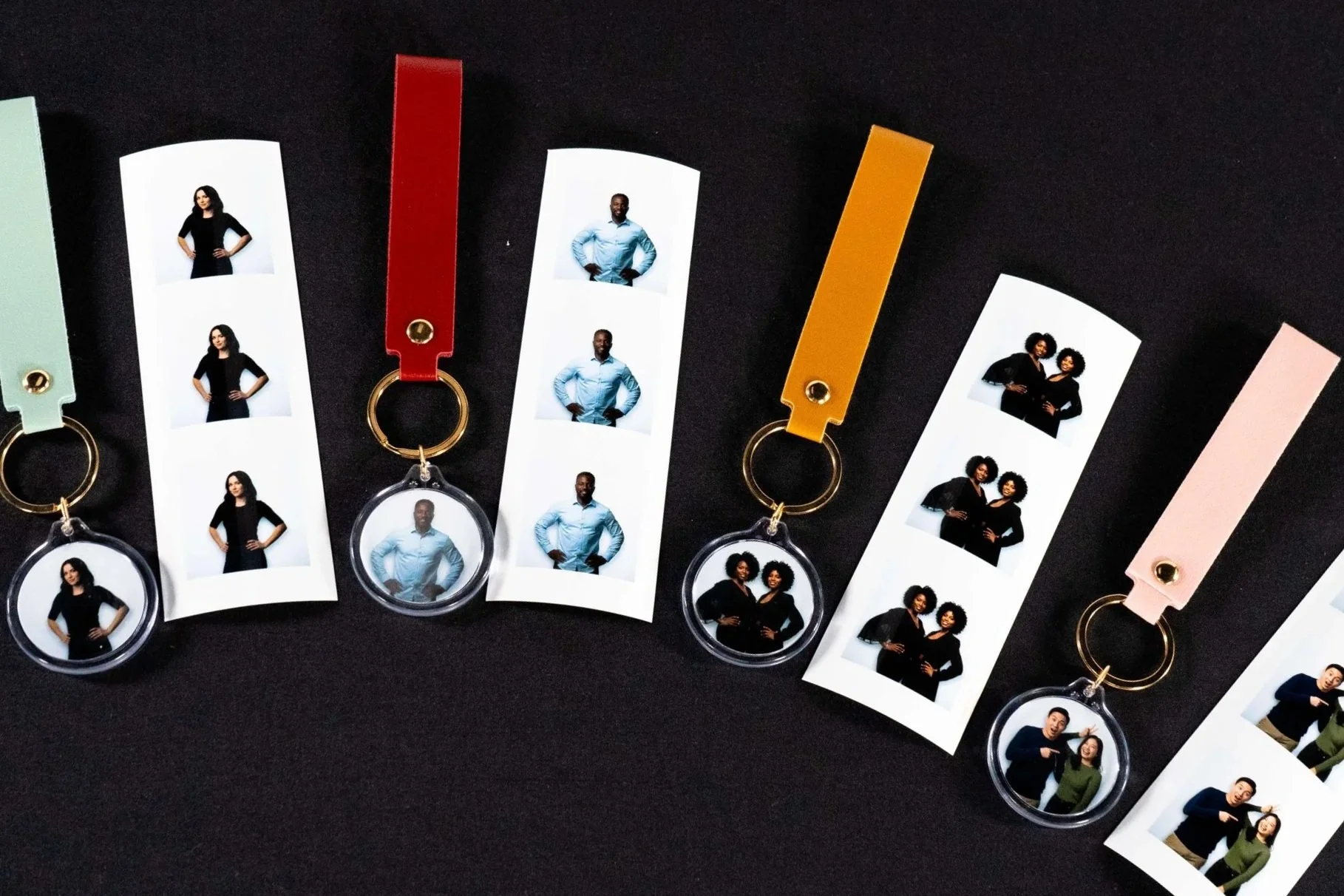 Keychains with photo strips of diverse people on a black background.