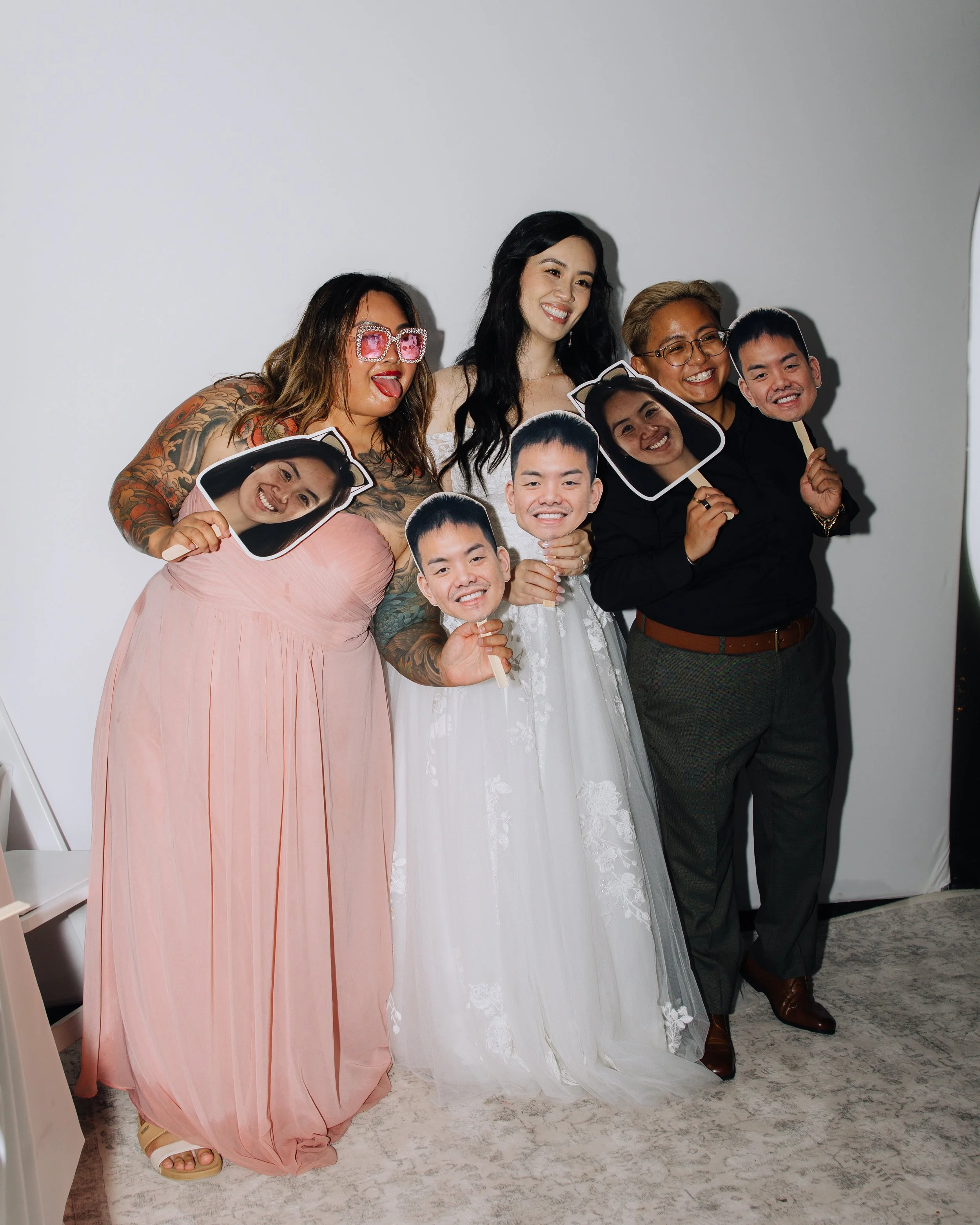 Bridesmaids and wedding guests posing together with oversized face props in the photo booth.