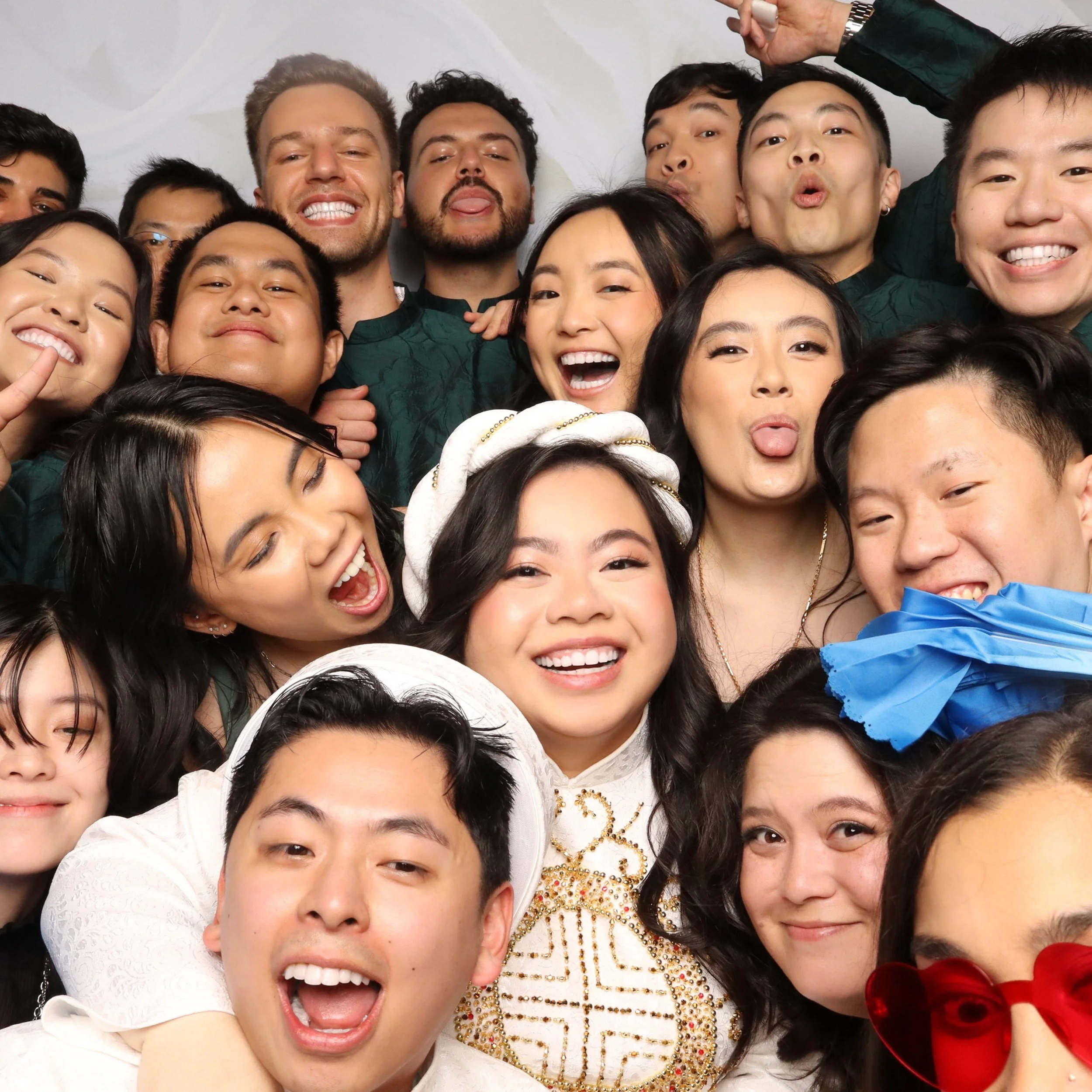 A group of diverse young people smiling, making silly faces, and posing closely together for a photo.