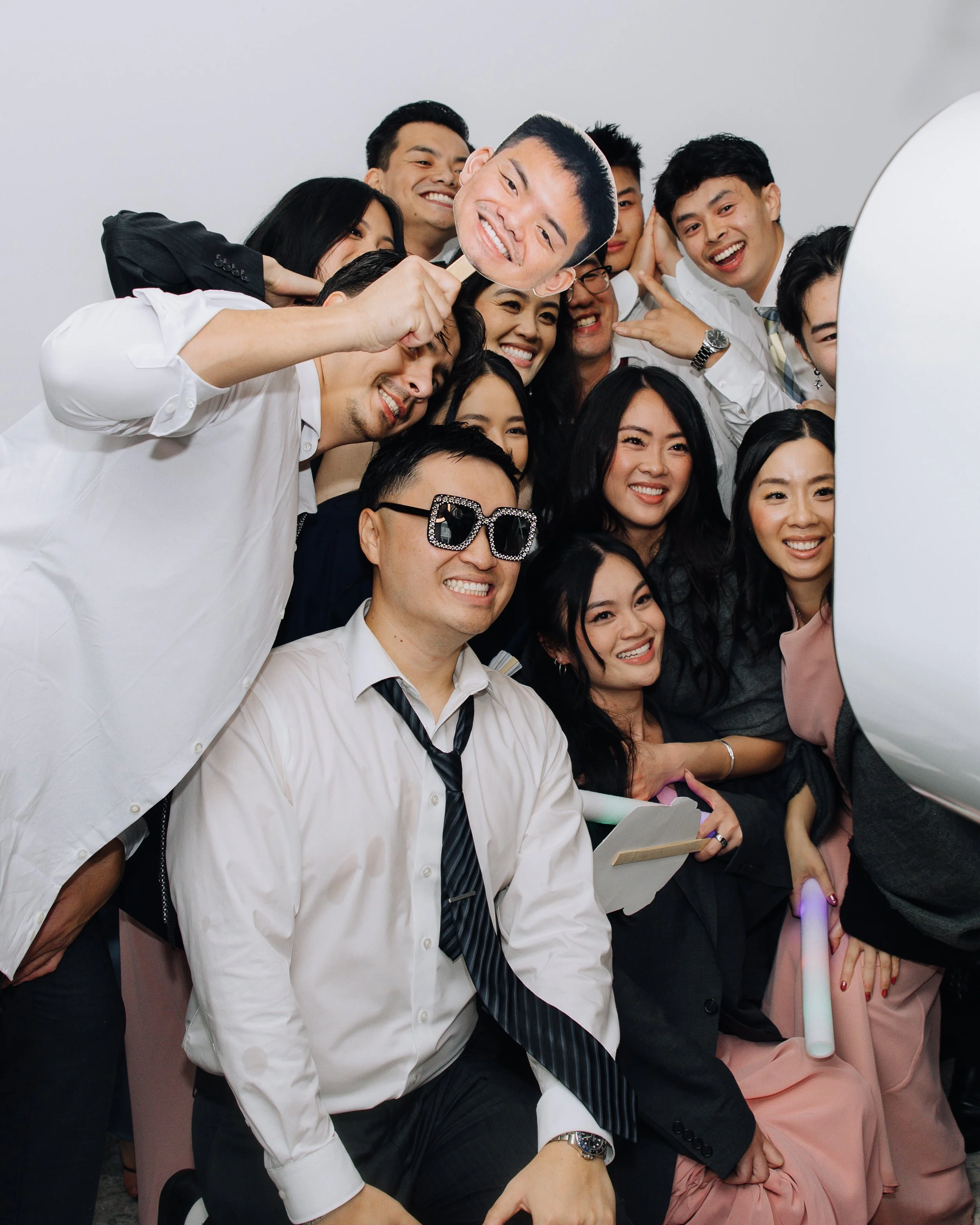 Bride and wedding guests posing with oversized face cutout props in the photo booth.