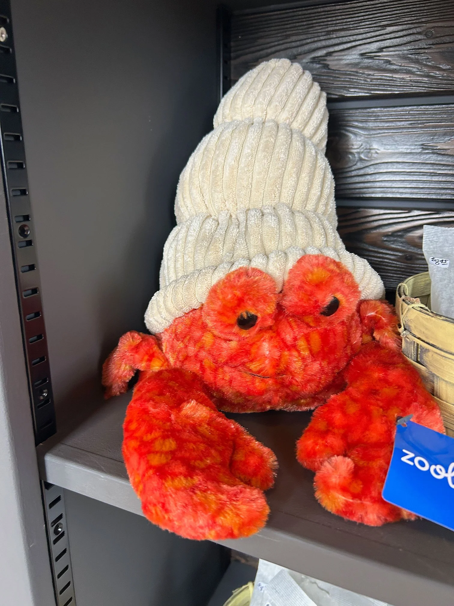 A display of plush orange and yellow Halloween pumpkin decorations and beige textured slippers on a store shelf.