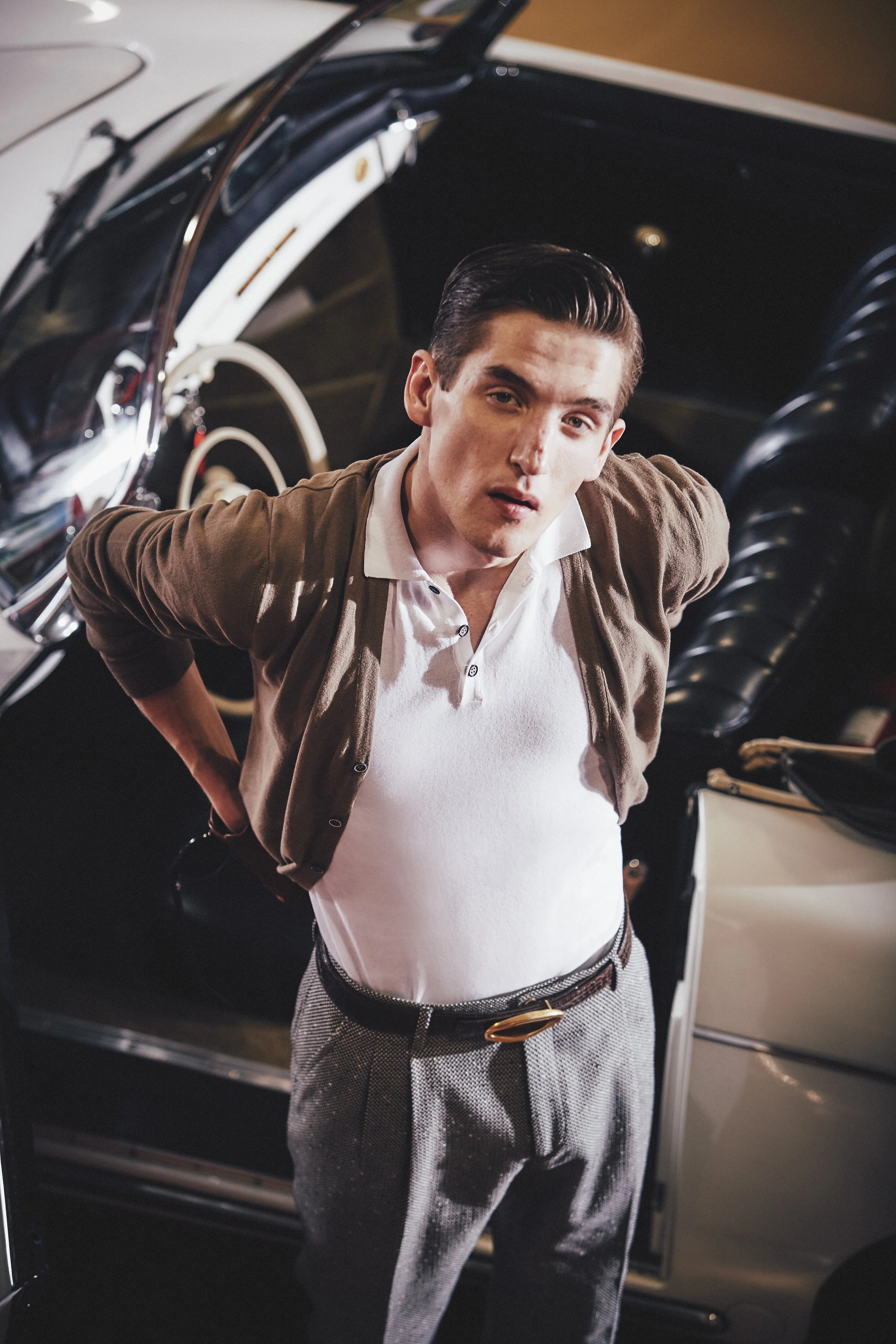 Modello in cardigan marrone e polo bianca davanti a un'auto d'epoca, fotografia moda uomo per Biagio Santaniello.