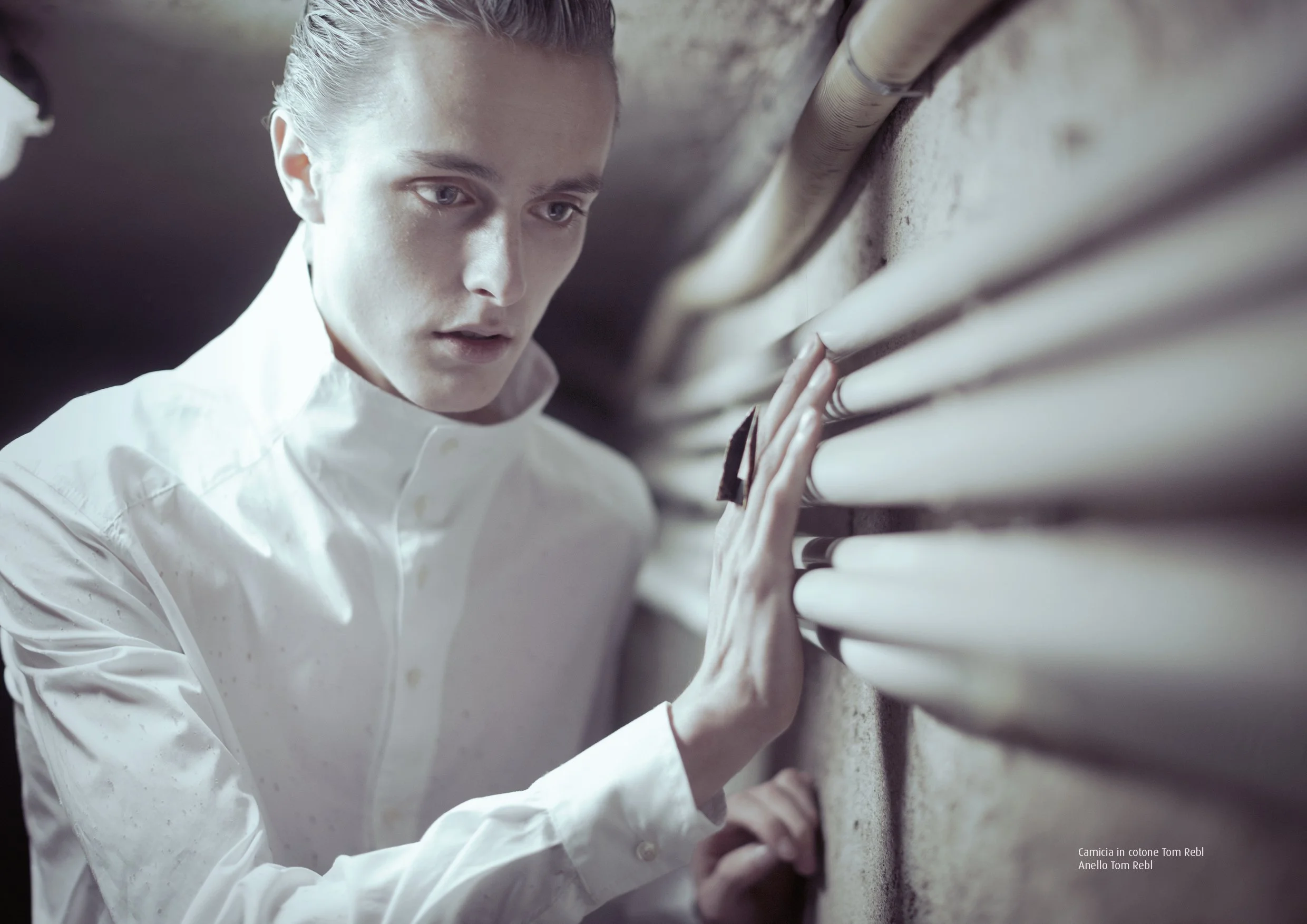 Modello in camicia bianca fotografato accanto alle tubature di un corridoio industriale, serie Underground Disorder di Paolo Esposito.