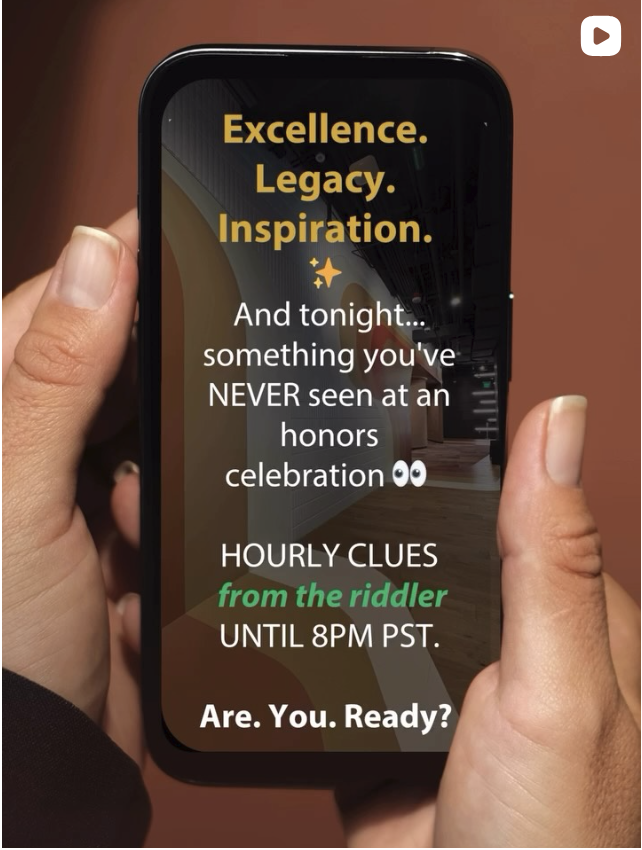 A person holding a smartphone displays a social media post with text about an honors celebration and hourly clues from a riddler, ending at 8 PM PST.