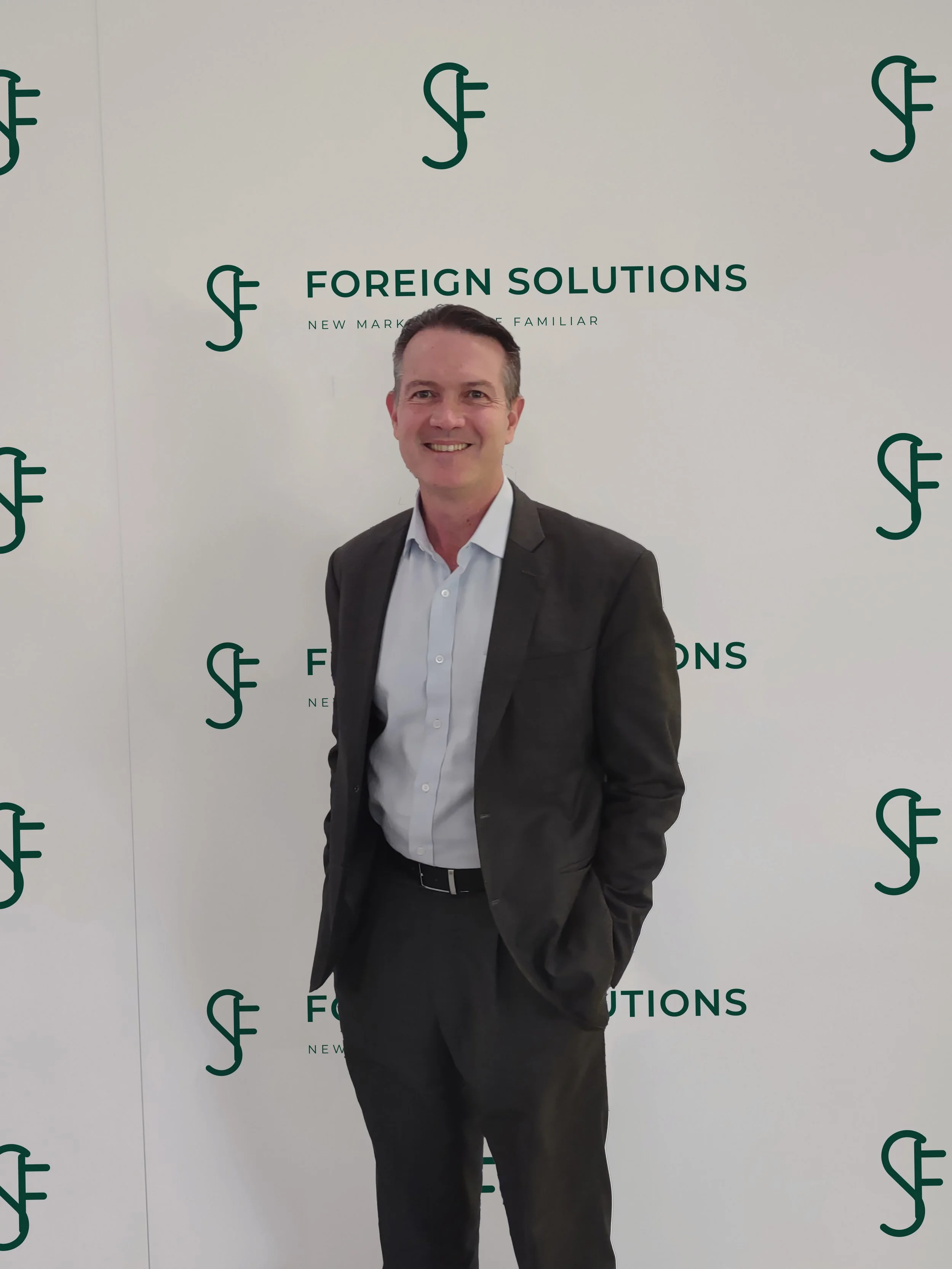 John Goebel in front of Foreign Solutions Logo wall