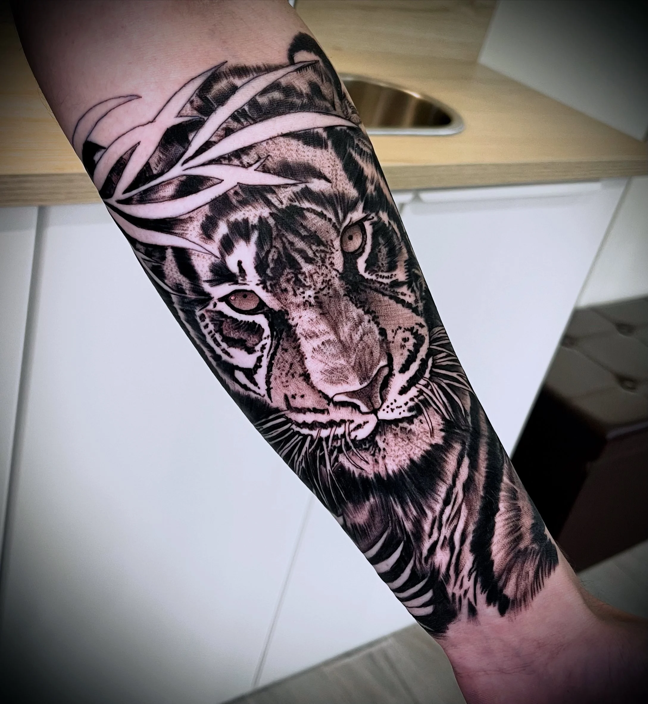Tattoo of a tiger's face on person's forearm with detailed black and gray shading.