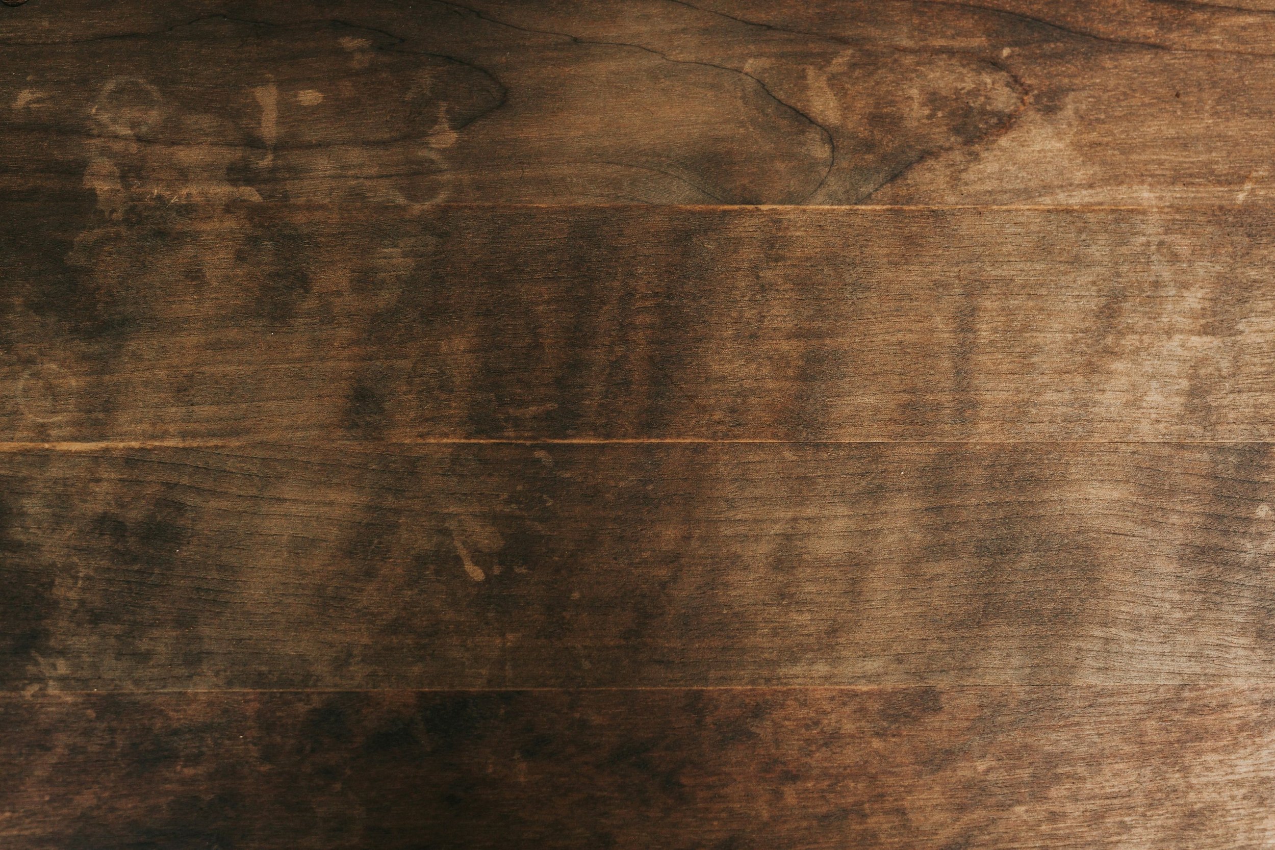 Superficie de madera oscura con vetas y manchas.