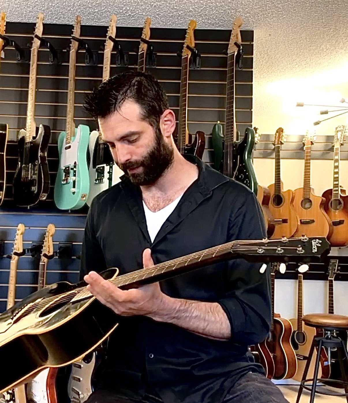 Max Seidman of Bennett Instruments inspecting a vintage Gibson guitar for originality and condition