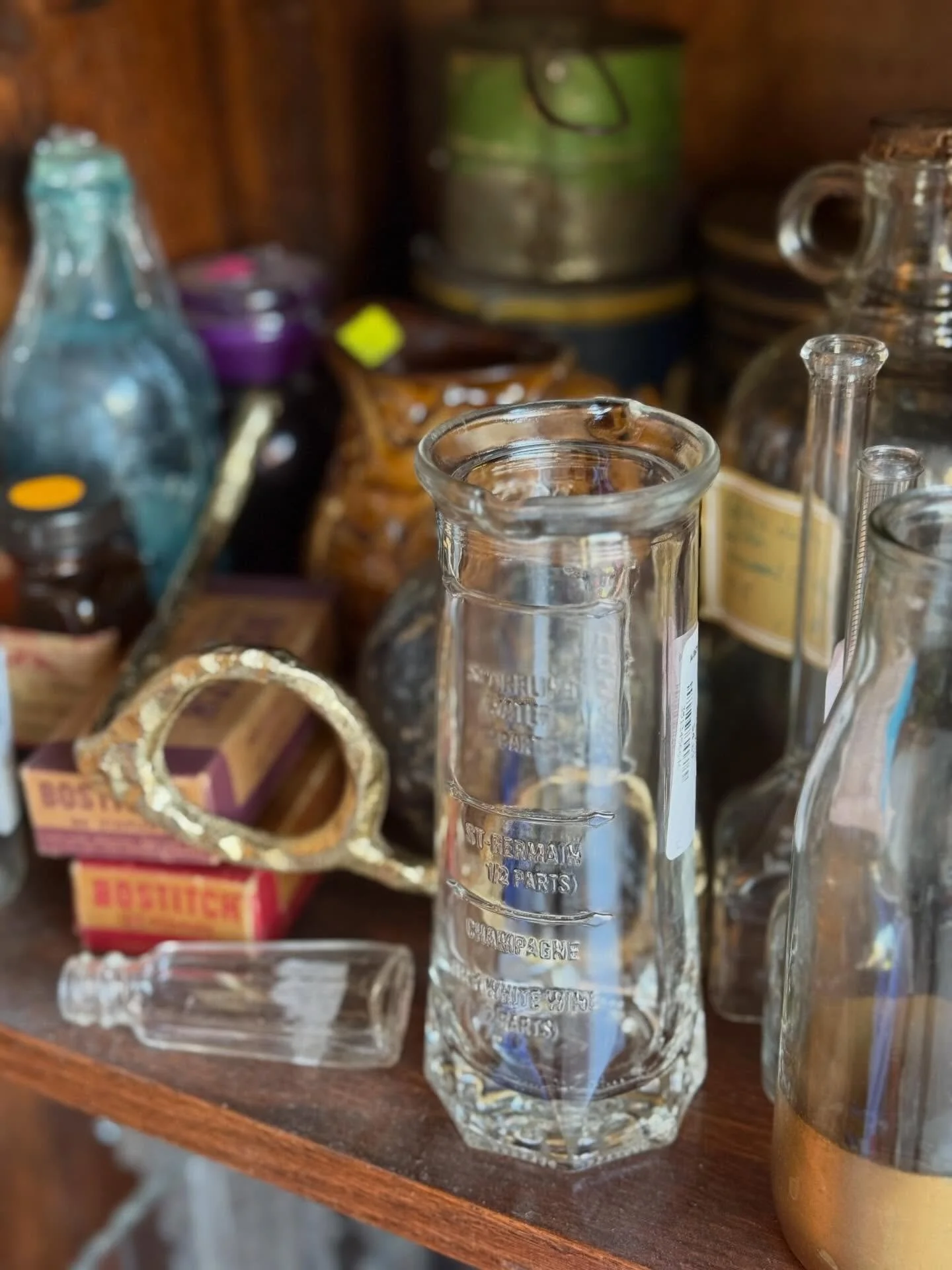 Close-up of empty glass laboratory test tubes on a wooden shelf with various bottles and containers in the background.
