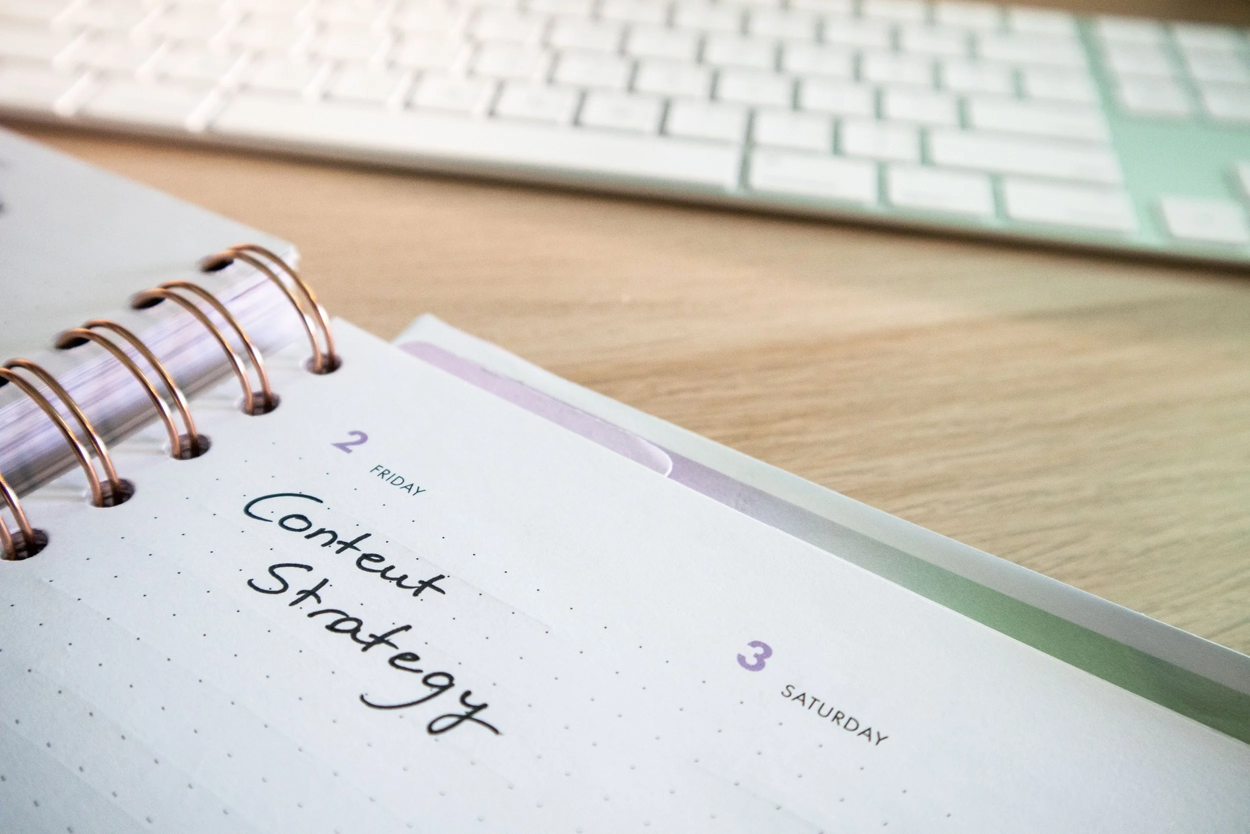 Close-up of a weekly planner page for Saturday, with handwritten text. A portion of a keyboard is visible in the background.