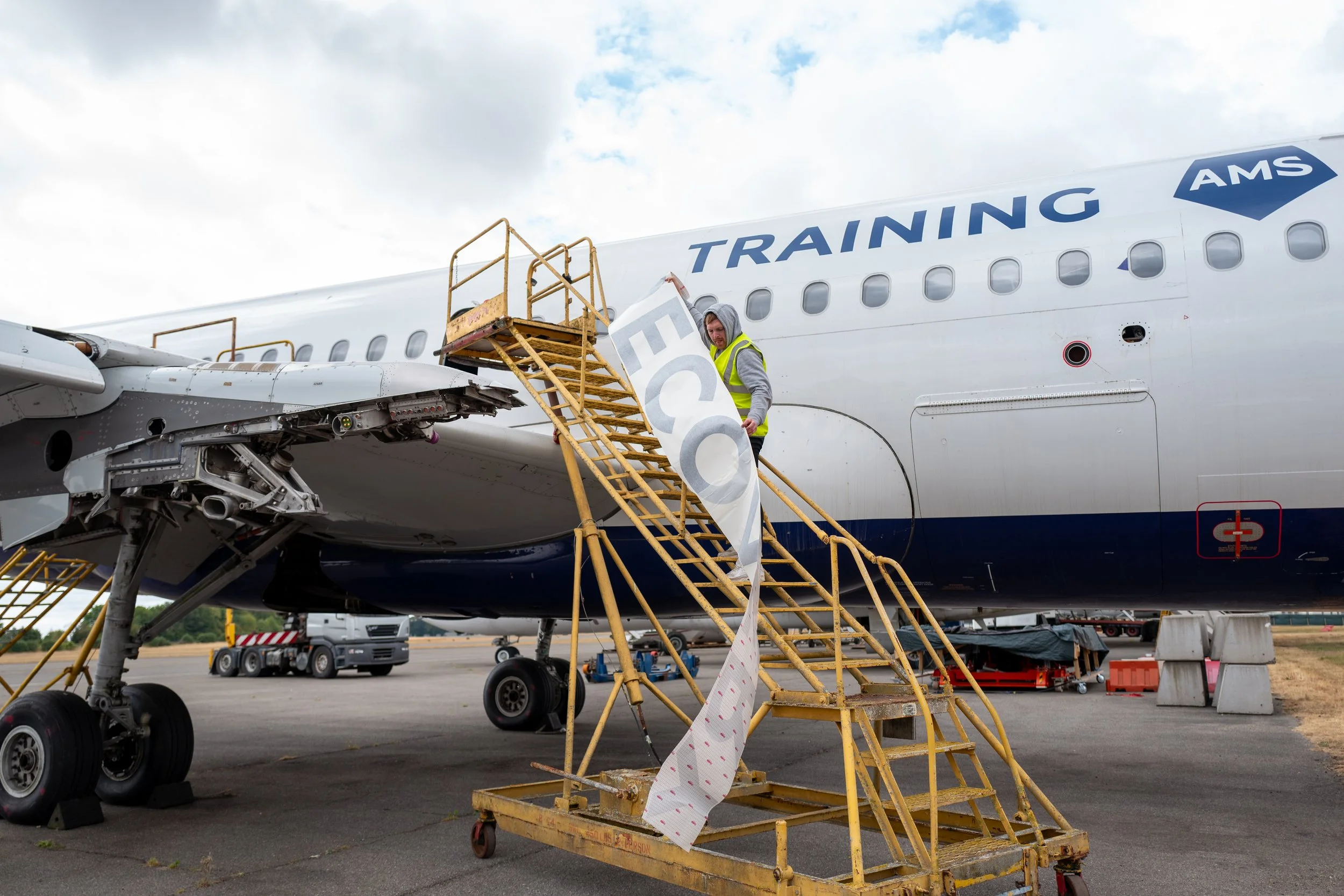 Installer positioning vinyl livery graphics on an aircraft fuselage