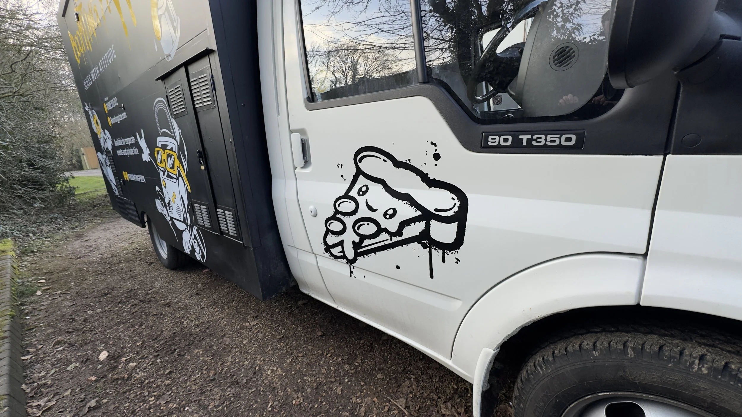Close-up of illustrated pizza slice decal on the white cab door.jpeg