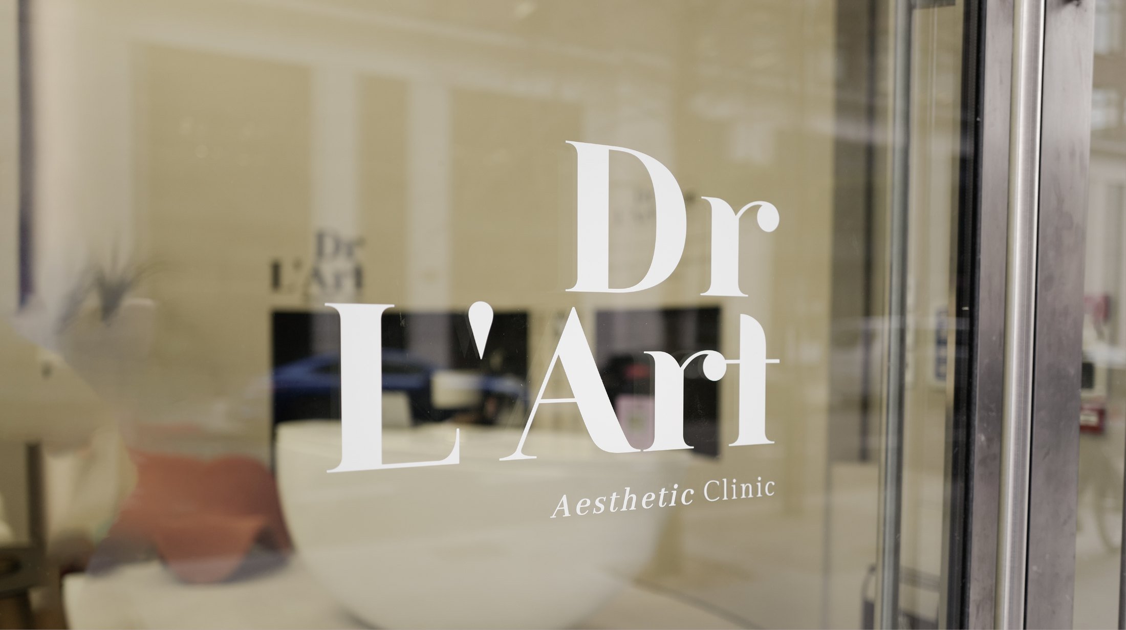 Glass door with white text displaying 'Dr. Lza r Aesthetic Clinic'.