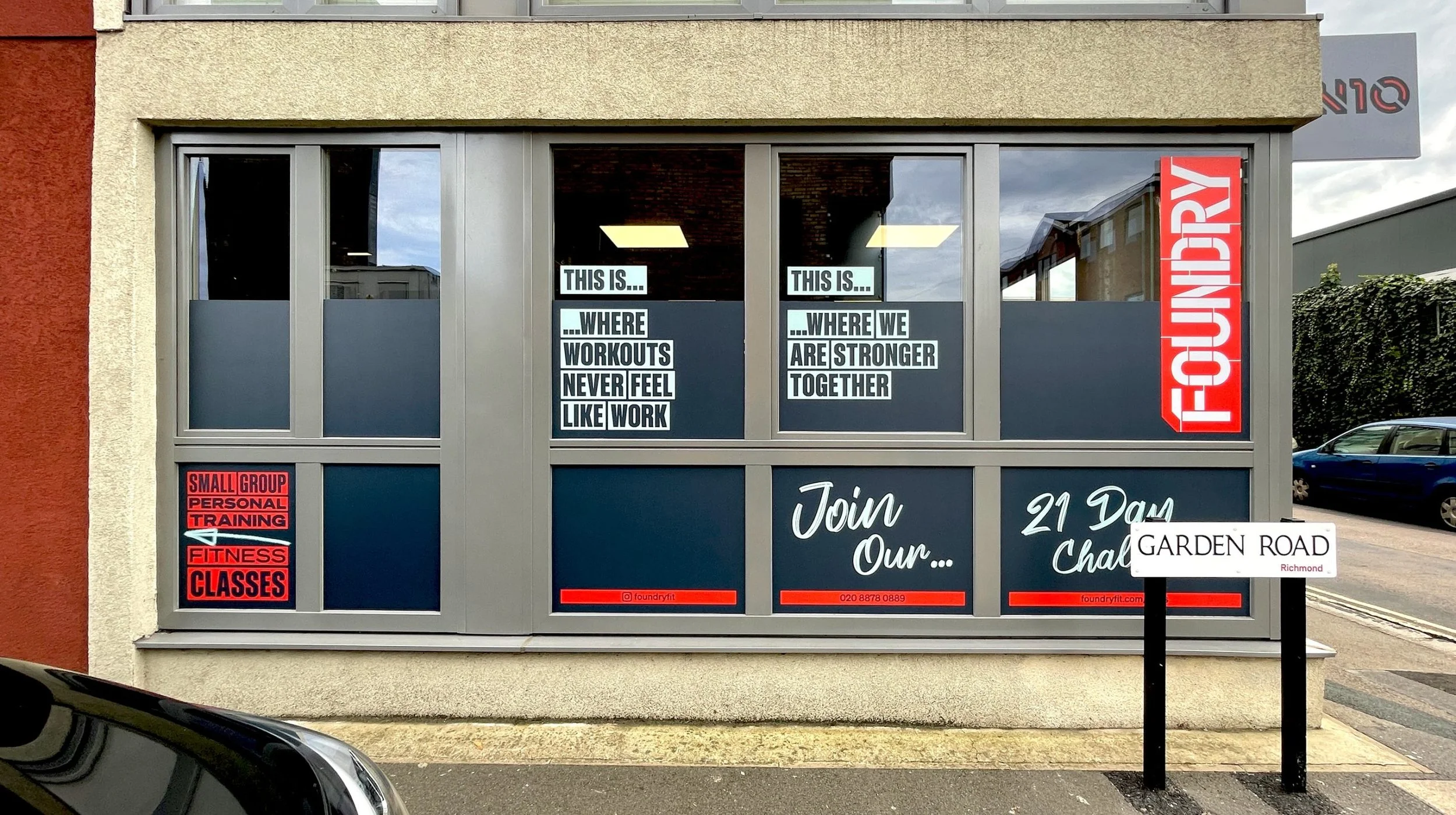 Signage on a building advertising a fitness training center with notice about workout locations and times, and a nearby sign for Garden Road in Richmond.