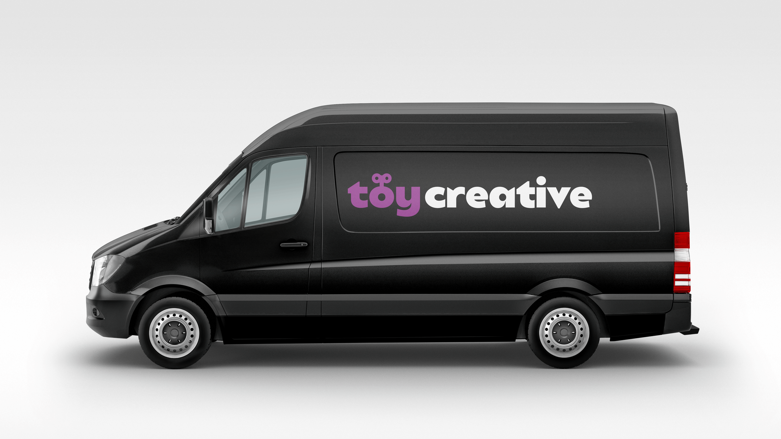 Black delivery van with 'toy creative' logo in purple and white on the side, against a plain light gray background.