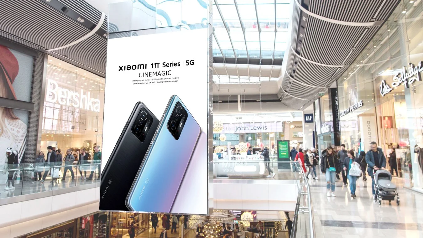 A large advertisement for Xiaomi 11T Series 5G smartphones displayed inside a shopping mall, with people walking in the background near various retail stores.