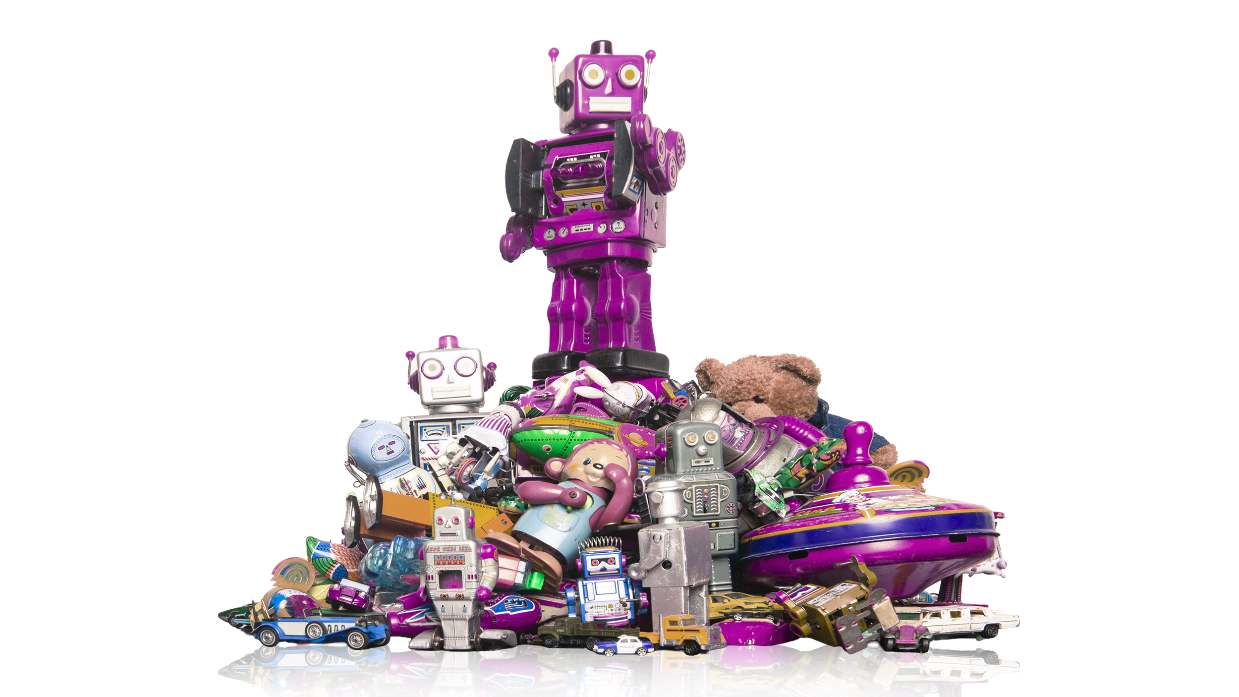 A pile of vintage toys including robots, cars, a teddy bear, and various colorful plastic objects.
