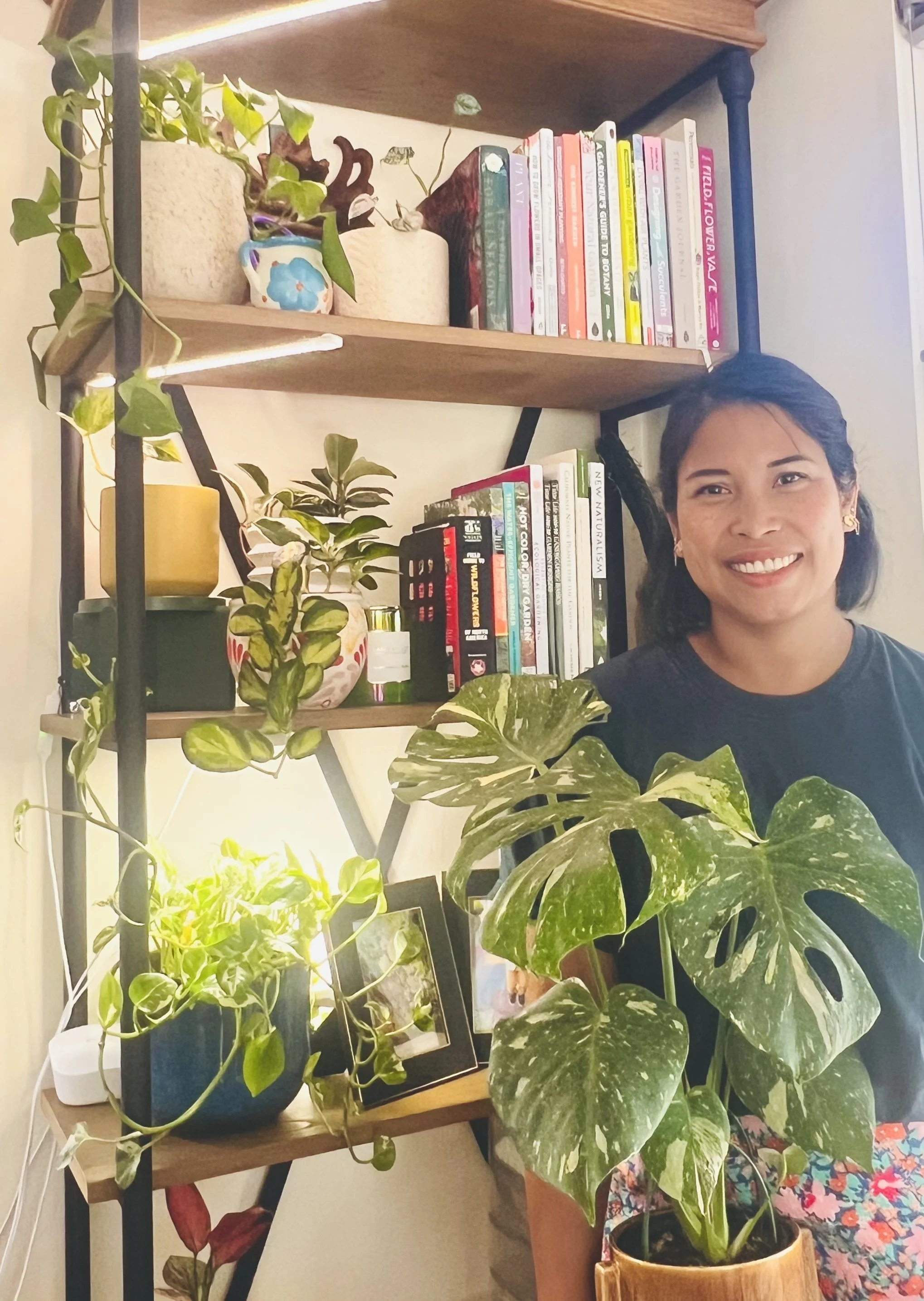 woman standing next to bookshelf styled with houseplants