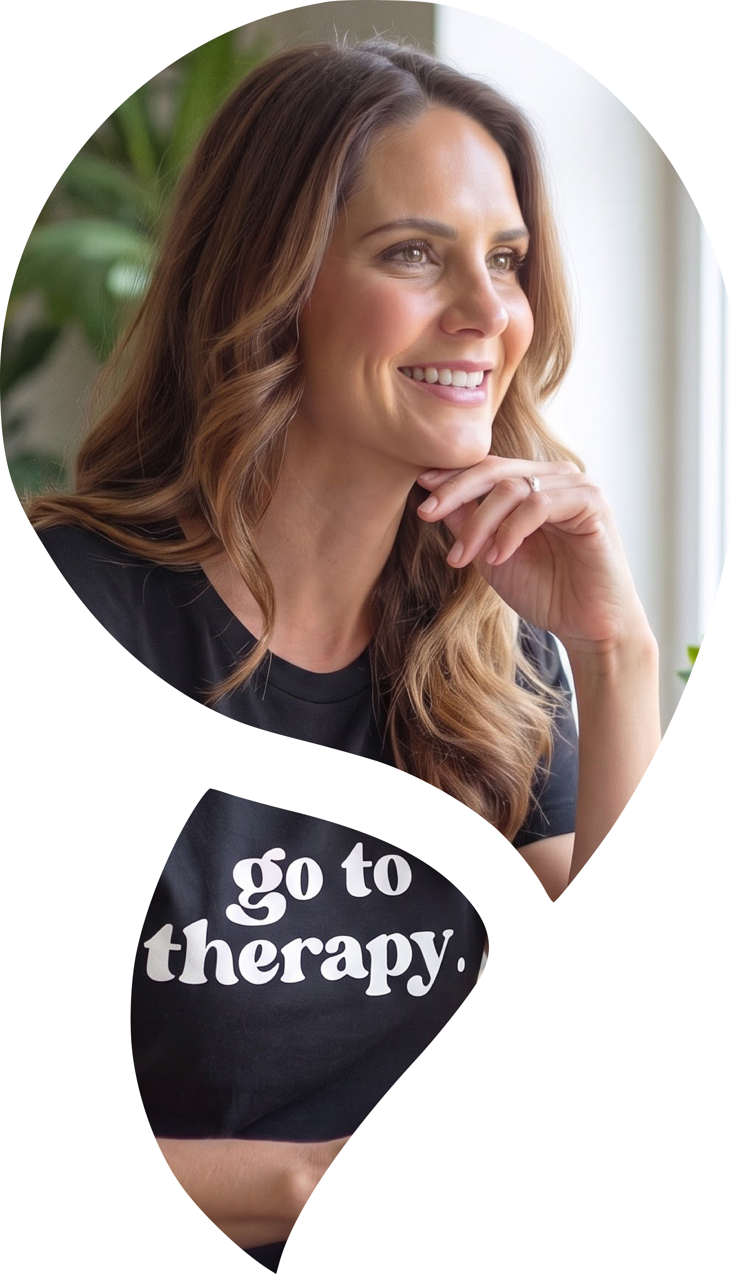 Kate Reddin, counsellor and executive coach at Comma + Co, smiling in a black blazer in warm indoor light.. She is wearing a black T-shirt with white text that reads 'go to therapy.'