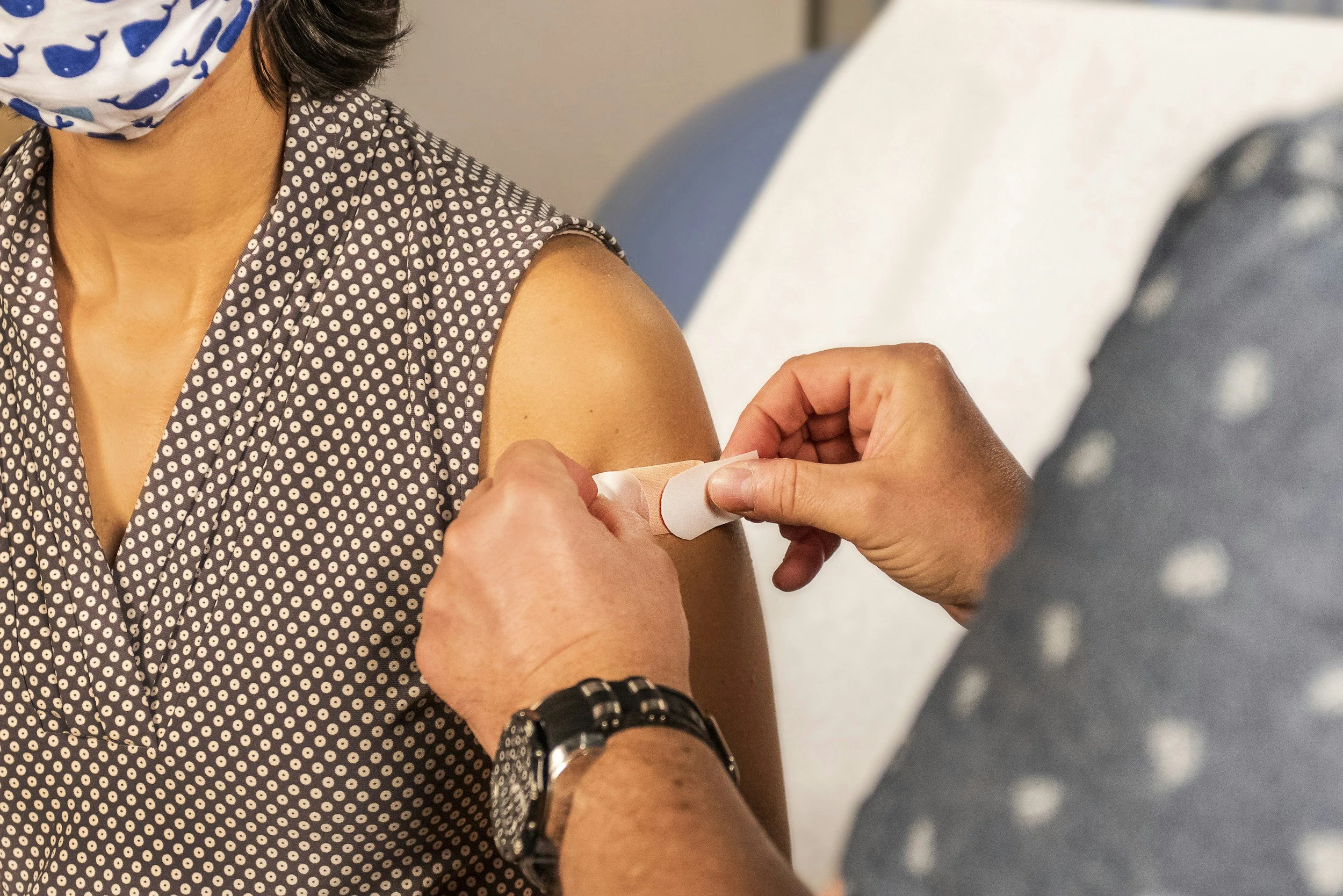 Person receiving a vaccination shot in their upper arm, with healthcare worker administering it.
