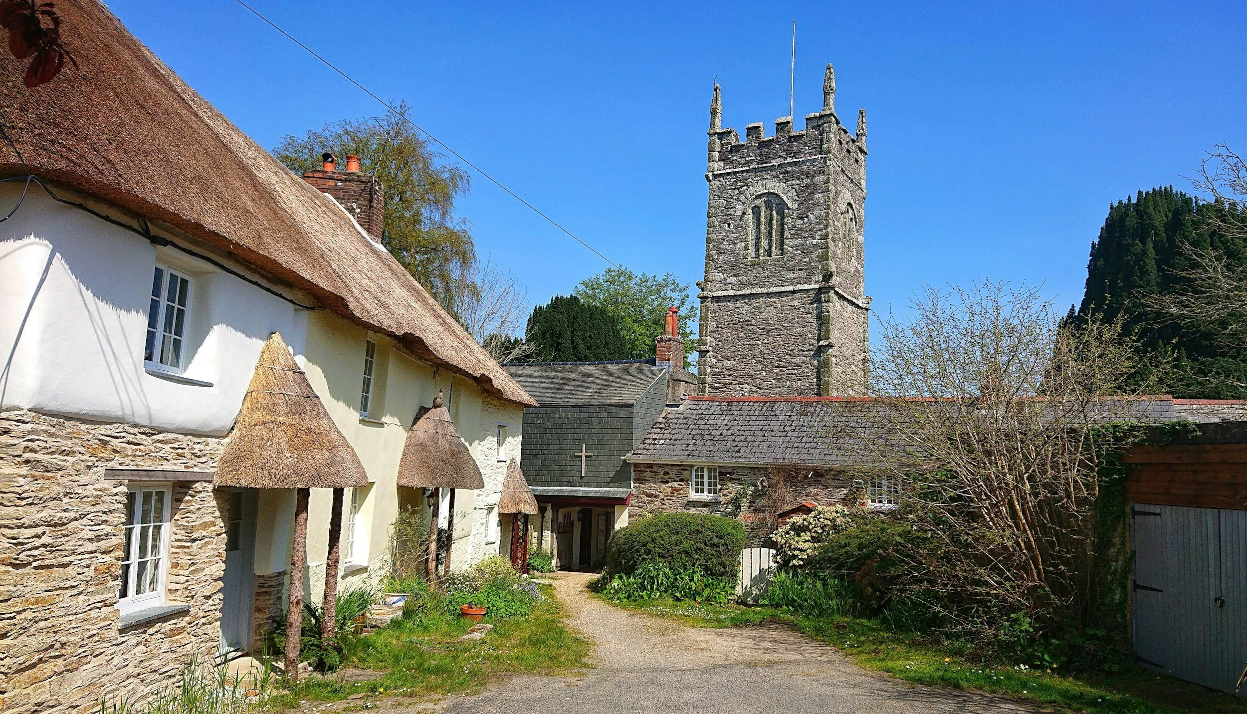 A scenic view of a village with traditional cottages and a stone church tower.