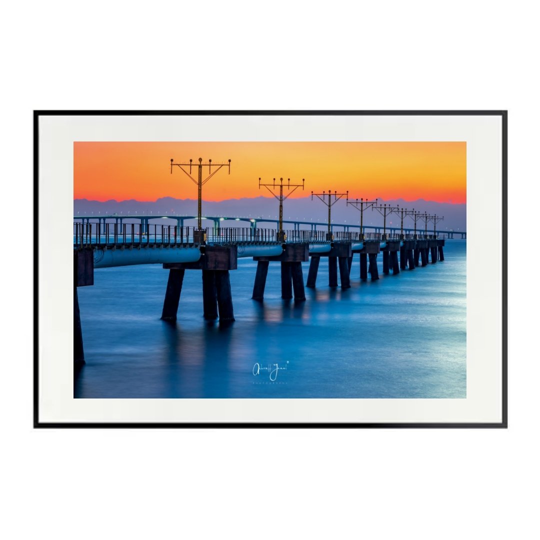 Blue Hour Radiance AJ8399 fine art photo by Ashraff Jamal, showcased in a modern black frame with a wide white mat border, featuring the Hong Kong Airport landing lights pier at sunset.