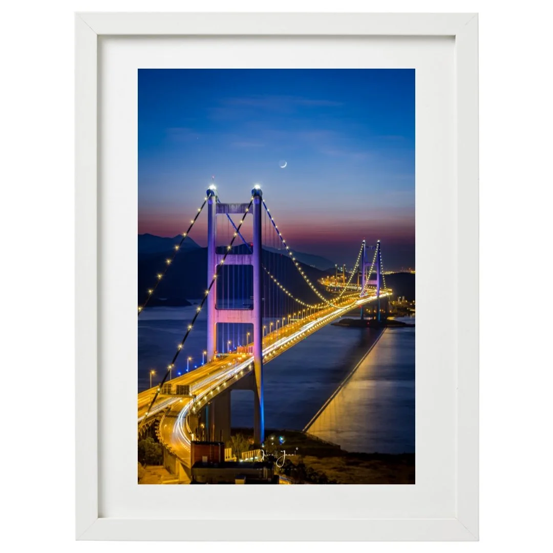 Polaroid-style vertical print of a suspension bridge at twilight with light trails.